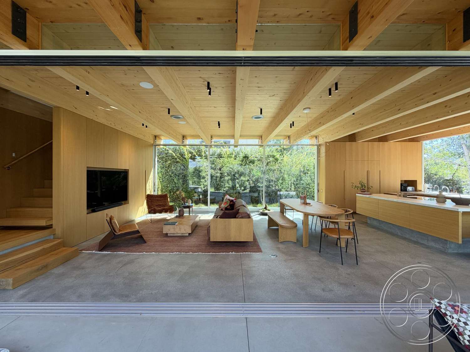 Retro House - textured area rug, wood paneling, concrete floor, modern coffee table, open concept living space, floating staircase, modern dining area, minimalist furniture design, exposed wooden ceiling beams, natural light-filled interior, glass wall with unobstructed view, integrated kitchen cabinetry, corner sofa seating, wood dining table with chairs