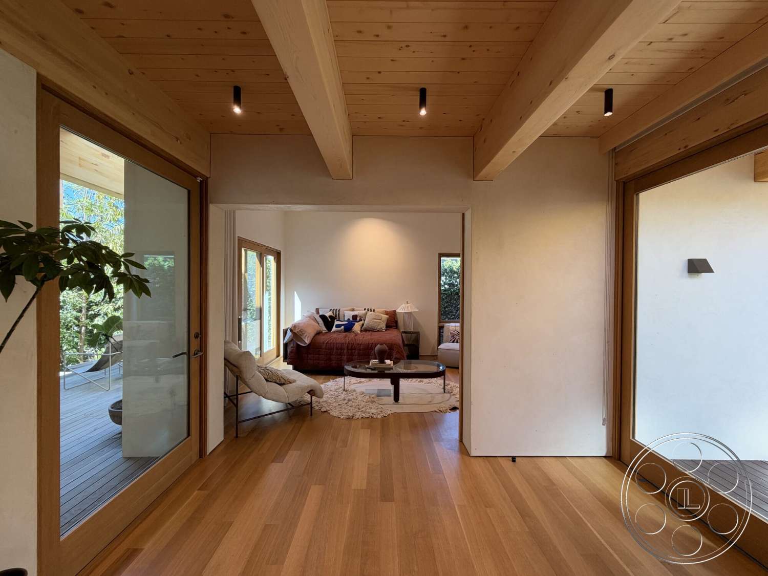 Retro House - natural light, contemporary design, open floor plan, light wood flooring, modern coffee table, minimalist furnishings, plaster wall treatment, wood beam ceiling, floor-to-ceiling glass doors, landscaped outdoor view, rug on hardwood floor, living room area with plush sofa