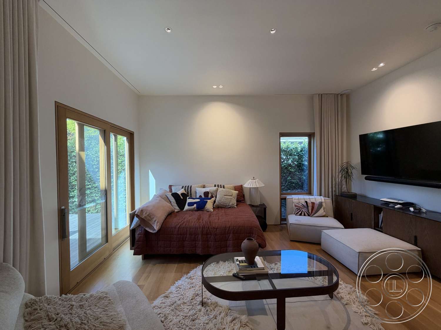 Retro House - indoor plant, warm color palette, floor-to-ceiling windows, decorative throw pillows, plush area rug, rectangular coffee table, simple bedside lamp, textured fabric curtains, white painted walls, modern television mounted on wall, exposed wood ceiling, light hardwood bedroom floors, built-in wooden dresser, contemporary style furniture
