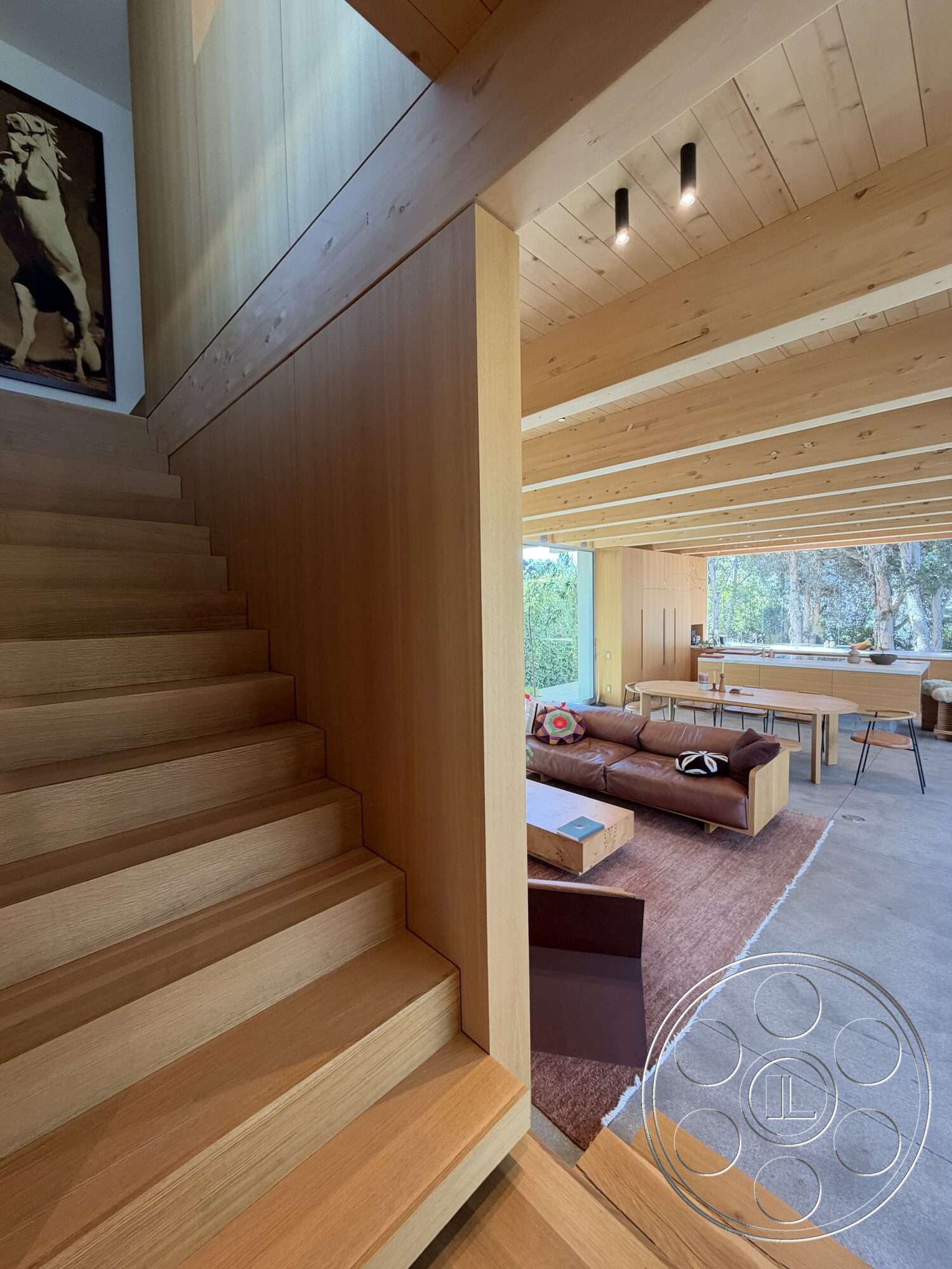 Retro House - wood dining table, large windows for natural light, plush area rug, rectangle coffee table, leather sectional sofa, exposed wood ceiling beams, contemporary furniture design, open concept living area, minimalist interior style, concrete floor finish, wood panel wall treatment, hardwood staircase steps