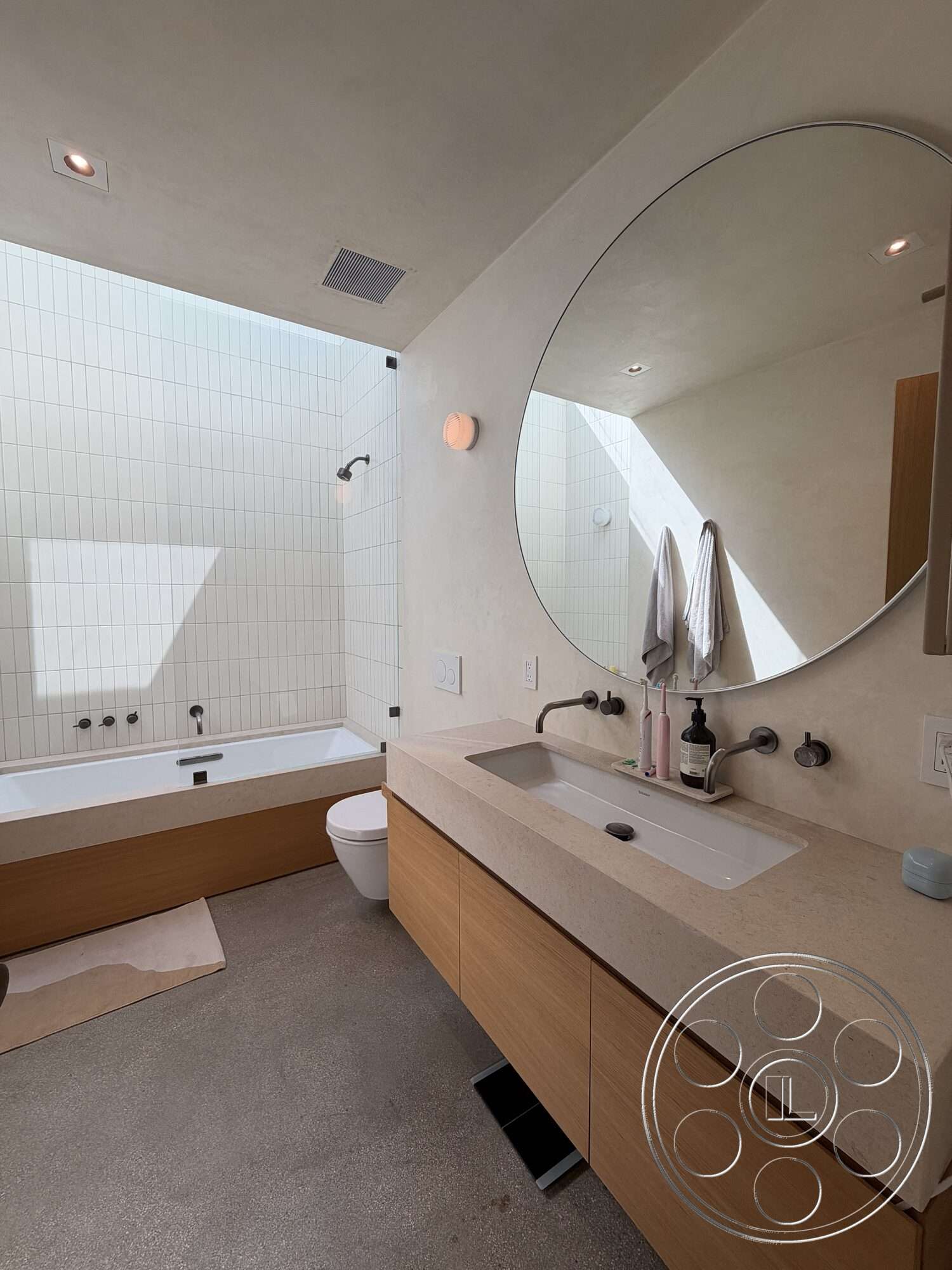 Retro House - freestanding bathtub, textured plaster walls, interior bathroom, concrete bathroom flooring, minimalist lighting fixtures, glass shower panel, white tiled shower walls, custom wood vanity with quartz countertop, round mirror above vanity, modern wall-mounted faucet fixtures
