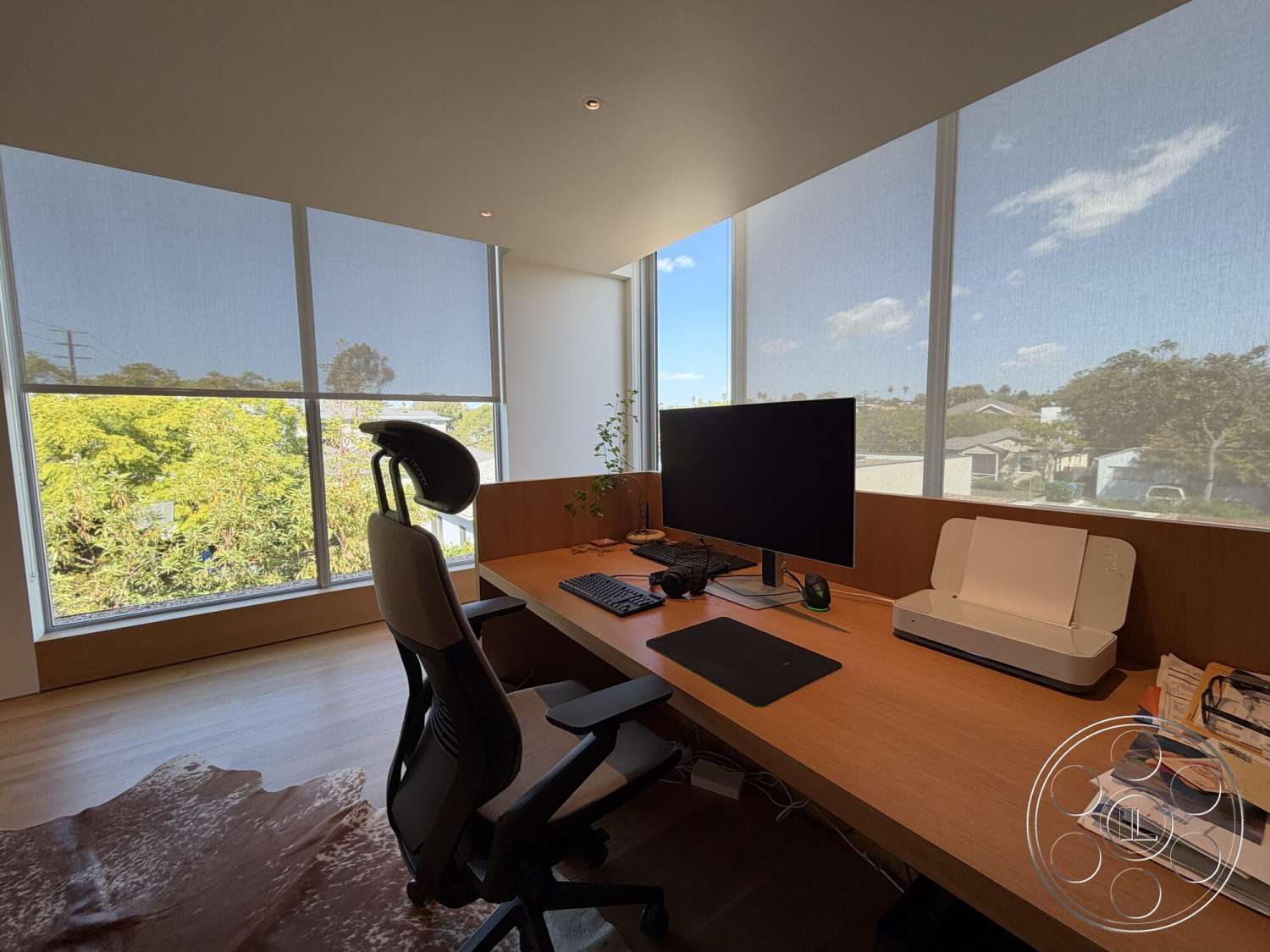 Retro House - minimalist decor, light wood flooring, modern workspace, large floor-to-ceiling windows, green potted plant, light-filtering window shades, wood office desk, black computer monitor, mesh ergonomic office chair