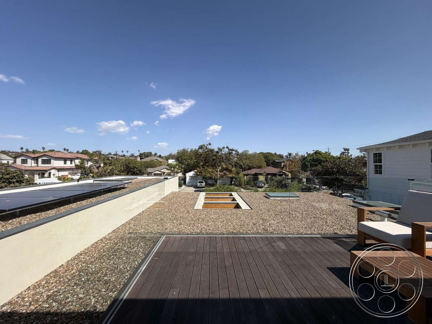 Retro House - exterior, gravel landscaping, flat roof design, wooden deck flooring, natural light exposure, open sky view, solar panel installation, minimalist outdoor seating, modern residential setting, suburban neighborhood view, rectangular plant beds, concrete wall barrier