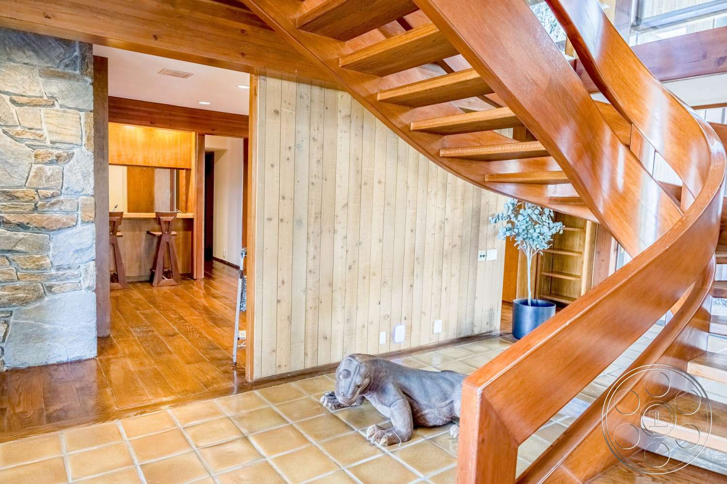 MCM 29 - tile flooring, open floor plan, wood ceiling beams, hardwood living room floors, textured wood paneling, exposed stone accent wall, wood spiral staircase