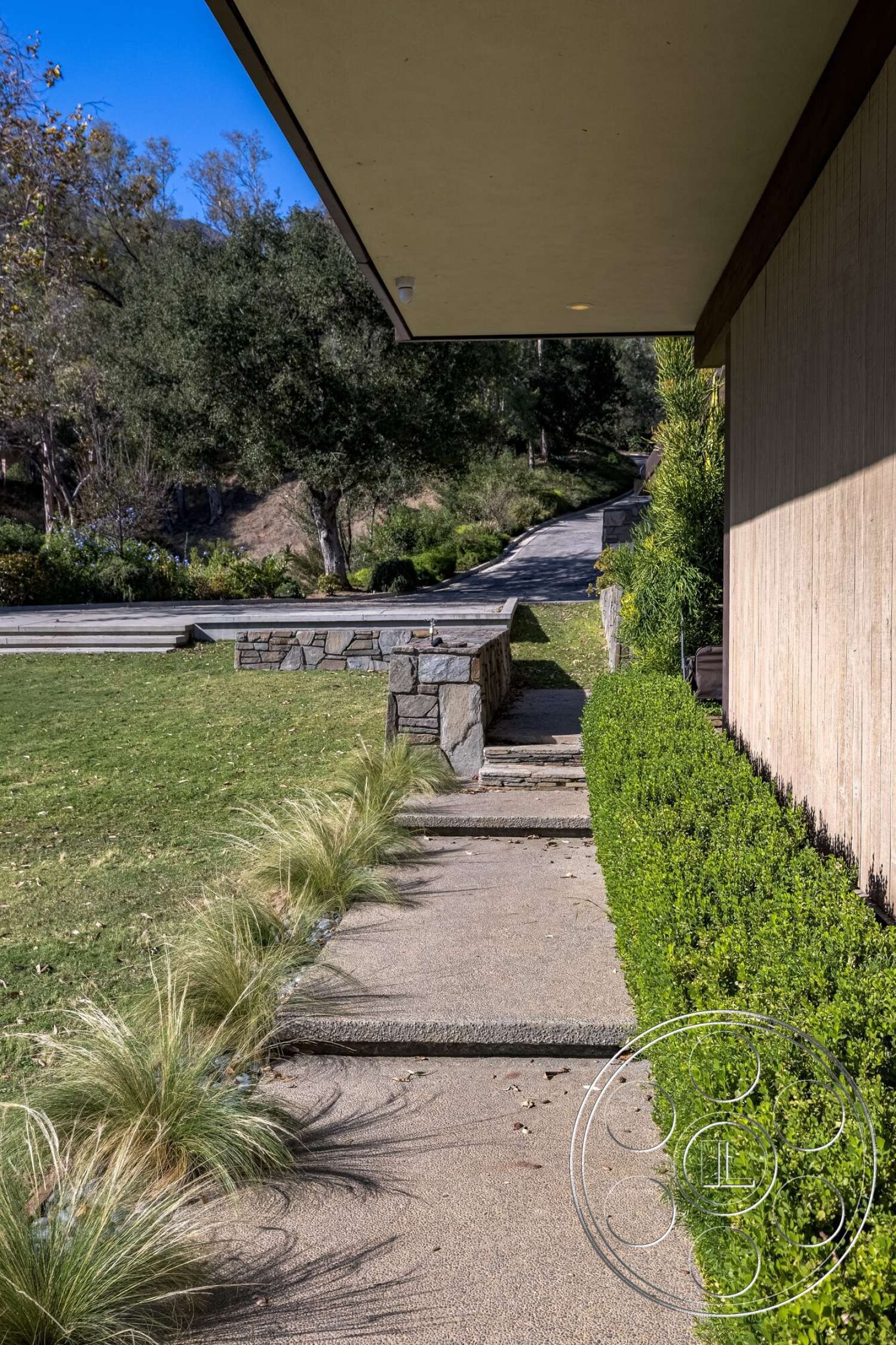 MCM 29 - exterior, landscaped garden, grassy lawn, modern architectural style, concrete walkway, textured concrete surface, low-maintenance shrubs, native landscaping, horizontal wood panel siding, stone wall border, pathway with grass inlays