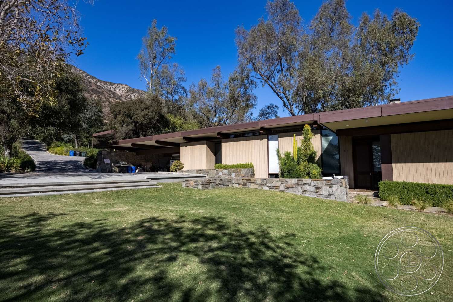 MCM 29 - large windows, exterior, wood paneling, mountain view, concrete driveway, mid-century modern architecture, flat roof design, landscaped garden area, rectangular lawn, stone facade walls