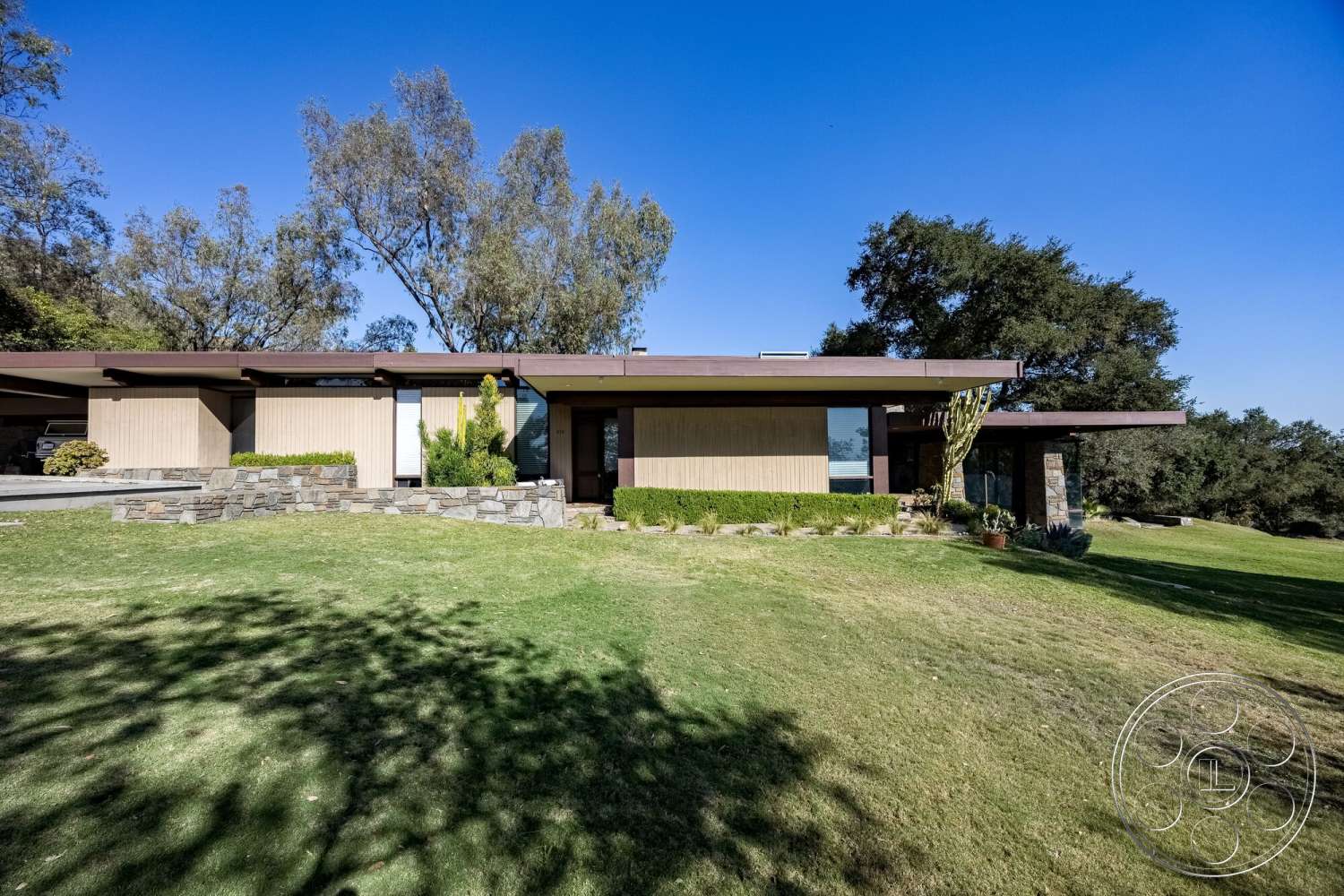 MCM 29 - exterior, landscaped garden, flat roof, minimalist design, panoramic windows, grassy lawn, modern architectural style, wood siding, bush landscaping, stone retaining wall, earth-toned facade