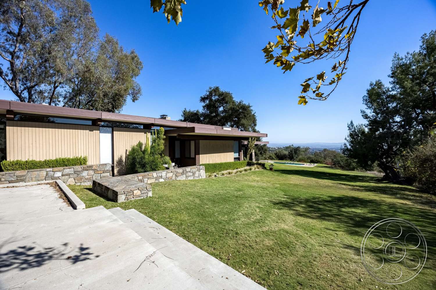 MCM 29 - exterior, surrounding trees, modern architectural style, landscaped lawn, concrete driveway, stone retaining wall, flat roof design, mountain view setting, wood siding exterior