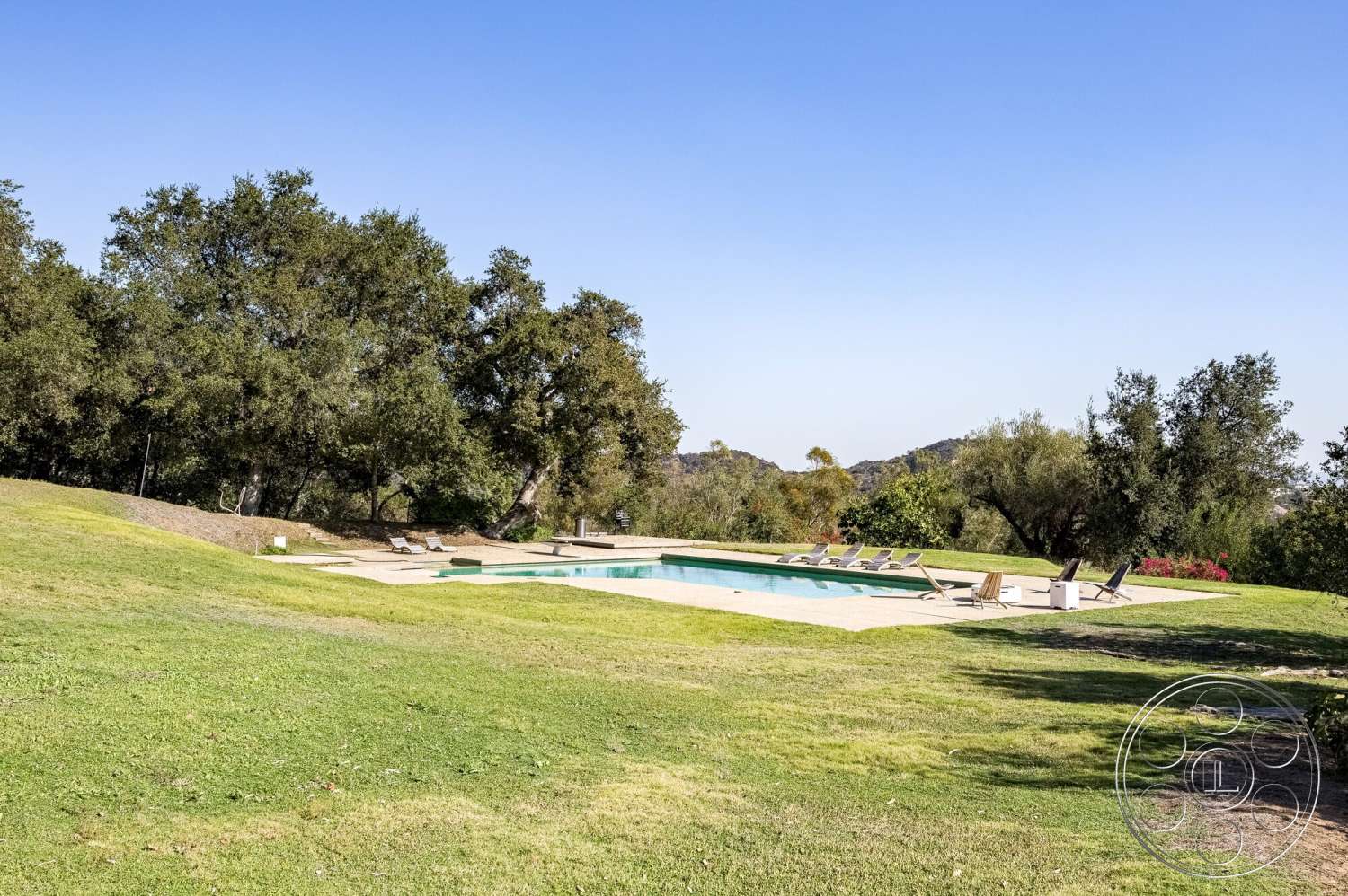 MCM 29 - exterior, mountain view, sun loungers, concrete pool deck, rectangular pool, surrounding oak trees, stone patio flooring, concrete pool border, lawn with green grass
