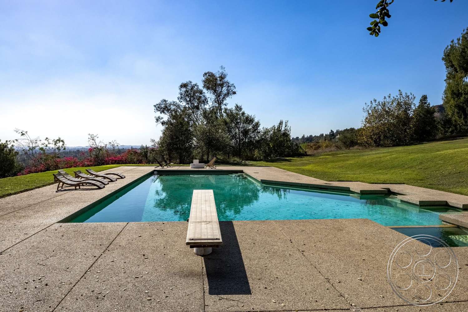 MCM 29 - exterior, concrete patio, surrounding trees, lawn, mountain view, clear blue sky, outdoor lounge chairs, concrete pool deck, rectangular pool, landscaped garden area, wood diving board