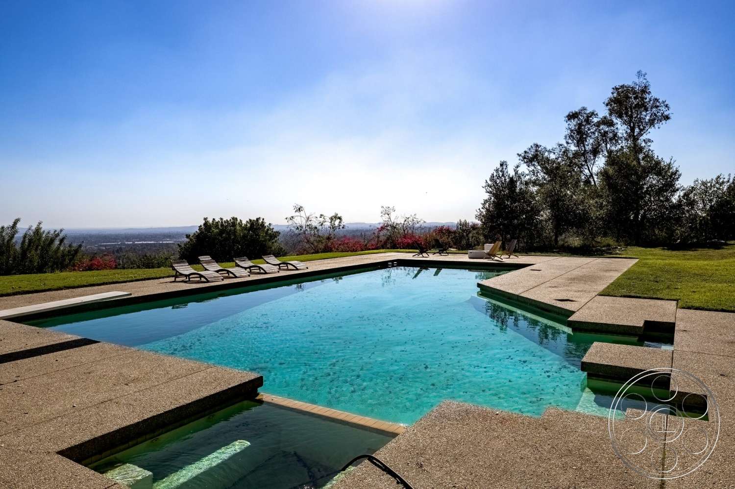 MCM 29 - exterior, natural vegetation, blue sky, outdoor lounge chairs, concrete pool deck, rectangular pool, hillside location, grass landscaping, distant city skyline view