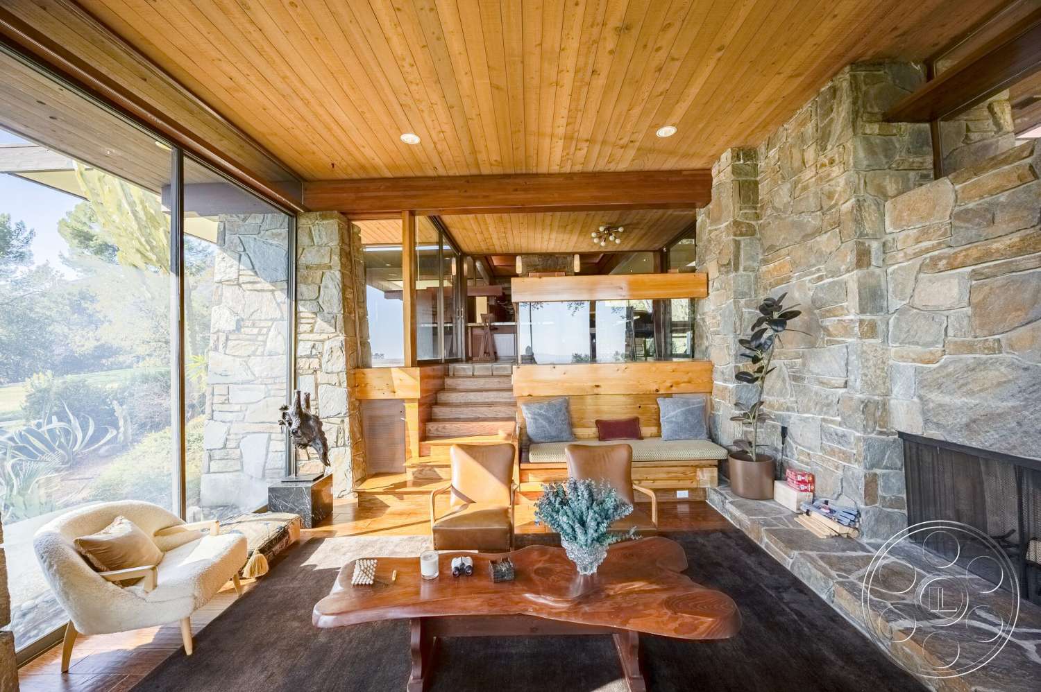 MCM 29 - neutral color palette, natural light, textured area rug, contemporary furniture, open floor plan, modern aesthetic, stone feature wall, floating staircase, hardwood living room floors, wood beam ceiling, stone fireplace surround, glass wall partition, wood seating bench