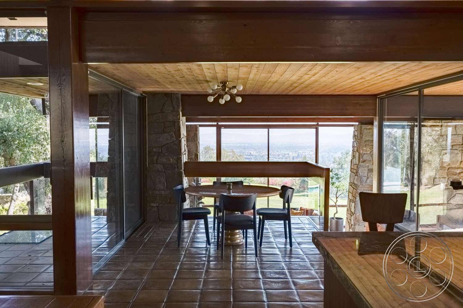 MCM 29 - natural light, exterior, open floor plan, glass sliding doors, wooden dining table, floor-to-ceiling windows, contemporary architecture, vaulted ceiling, city skyline view, ceramic tile floor, stone feature wall, black upholstered chairs, modern dining area, integrated indoor-outdoor flow, wood beam ceiling