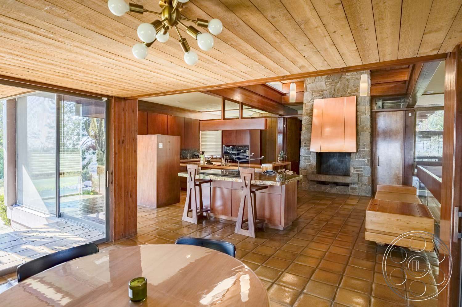 MCM 29 - modern pendant lighting, glass sliding doors, wood ceiling panels, open concept living space, mid-century modern architecture, slate tile flooring, granite kitchen countertops, natural light flooding in, exposed stone fireplace wall, floating wood cabinets, custom wood dining table