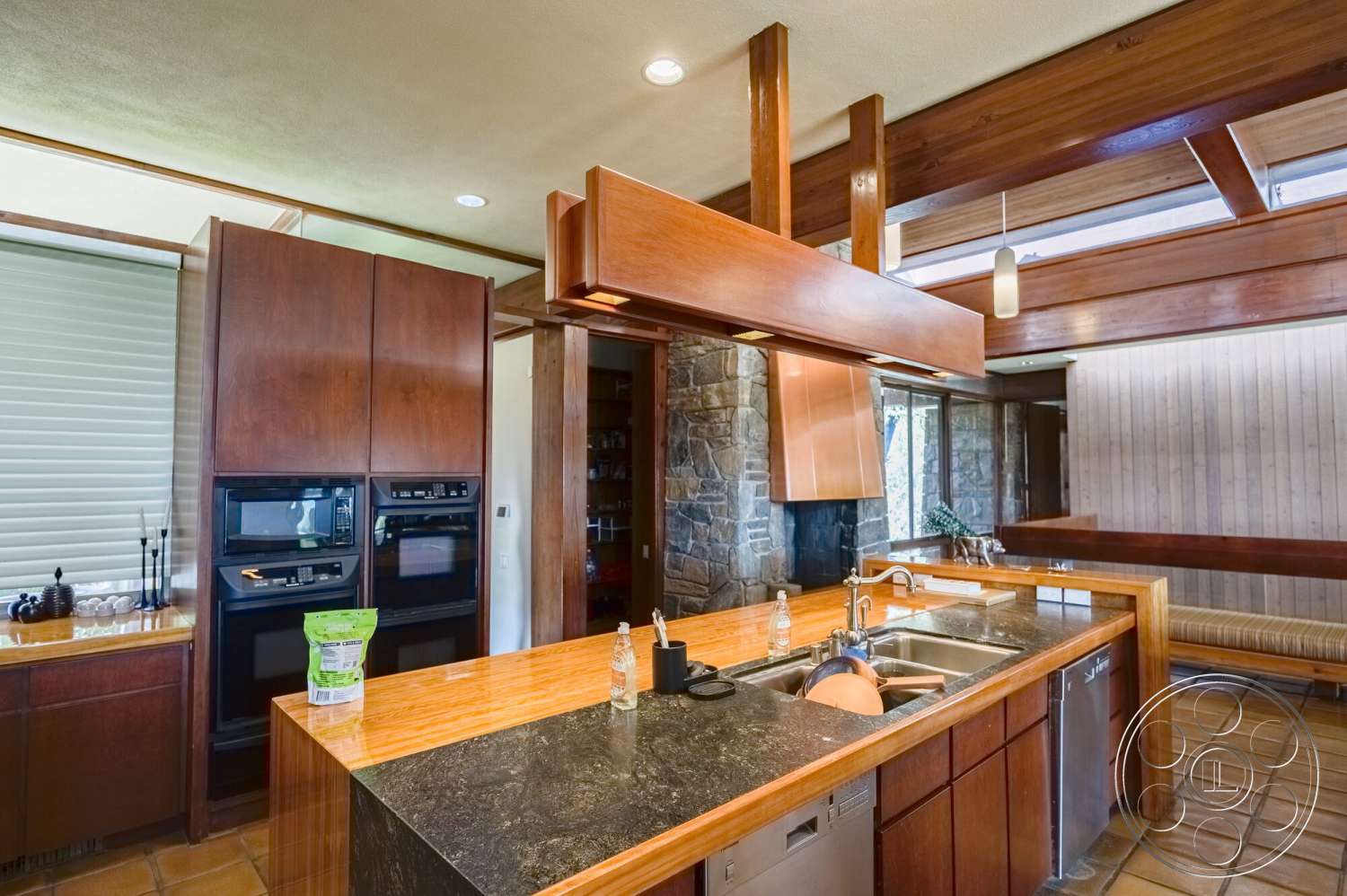 MCM 29 - stone accent wall, stainless steel appliances, wood cabinetry, sliding glass doors, open-concept layout, pendant lighting fixtures, exposed wood ceiling beams, granite kitchen countertops, tile kitchen flooring, dark wood kitchen cabinets