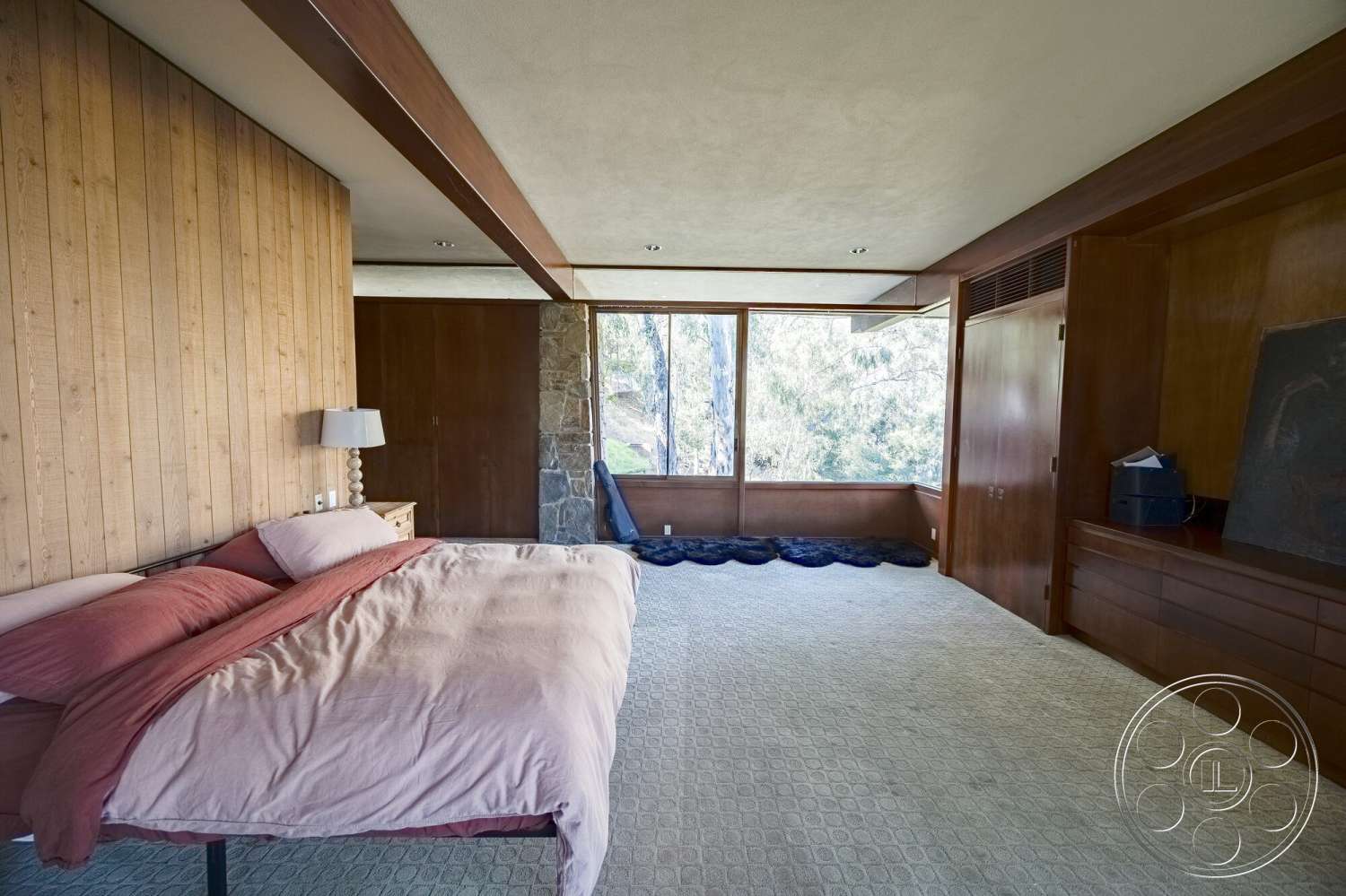 MCM 29 - exterior, floor-to-ceiling windows, mid-century modern architectural style, open floor plan layout, wood paneling accent wall, modern ceiling light fixtures, natural stone feature wall, carpet bedroom flooring, minimalist bedside lamp, built-in wooden storage cabinets, vaulted ceiling design, hardwood bedroom furniture, earthy color palette decor, bedroom with view