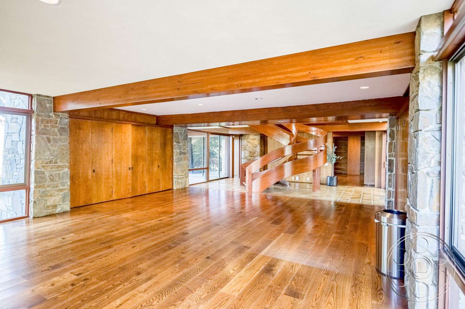 MCM 29 - natural light, hardwood flooring, stone accent wall, open floor plan, wood paneling, exposed wood beams, floor-to-ceiling windows, modern architectural style, curved staircase