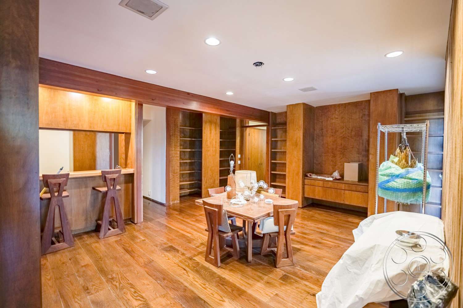 MCM 29 - natural light, minimalist design, open floor plan, elegant table setting, simple wooden dining table, dark wood paneling walls, wood beam ceiling, built-in wooden shelving, hardwood dining room floors, modern wooden bar stools