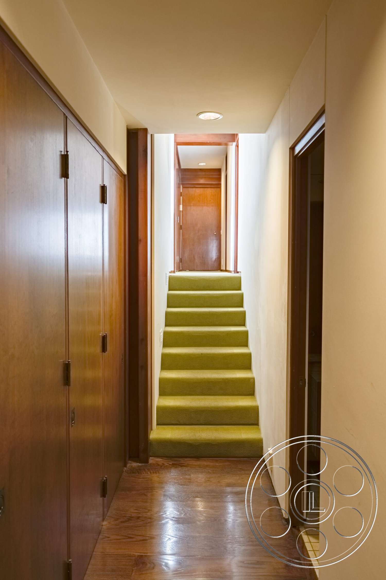MCM 29 - hardwood flooring, flush ceiling lights, interior hallway, modern interior design, wood paneling on walls, narrow hallway layout, wooden closet doors, olive green carpet stairs