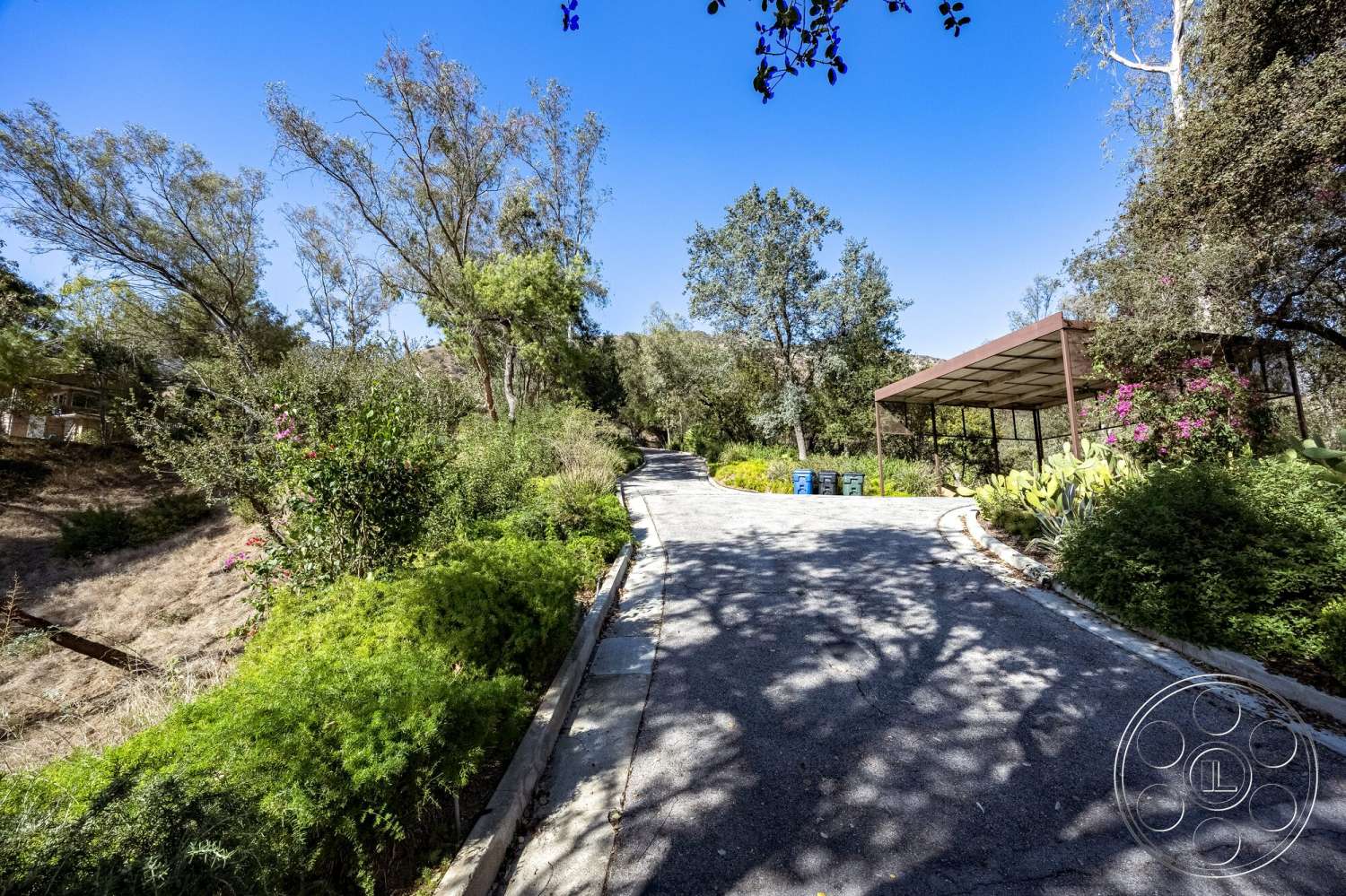 MCM 29 - landscaped garden, natural stone accents, surrounding greenery, curved driveway, asphalt driveway, metal carport