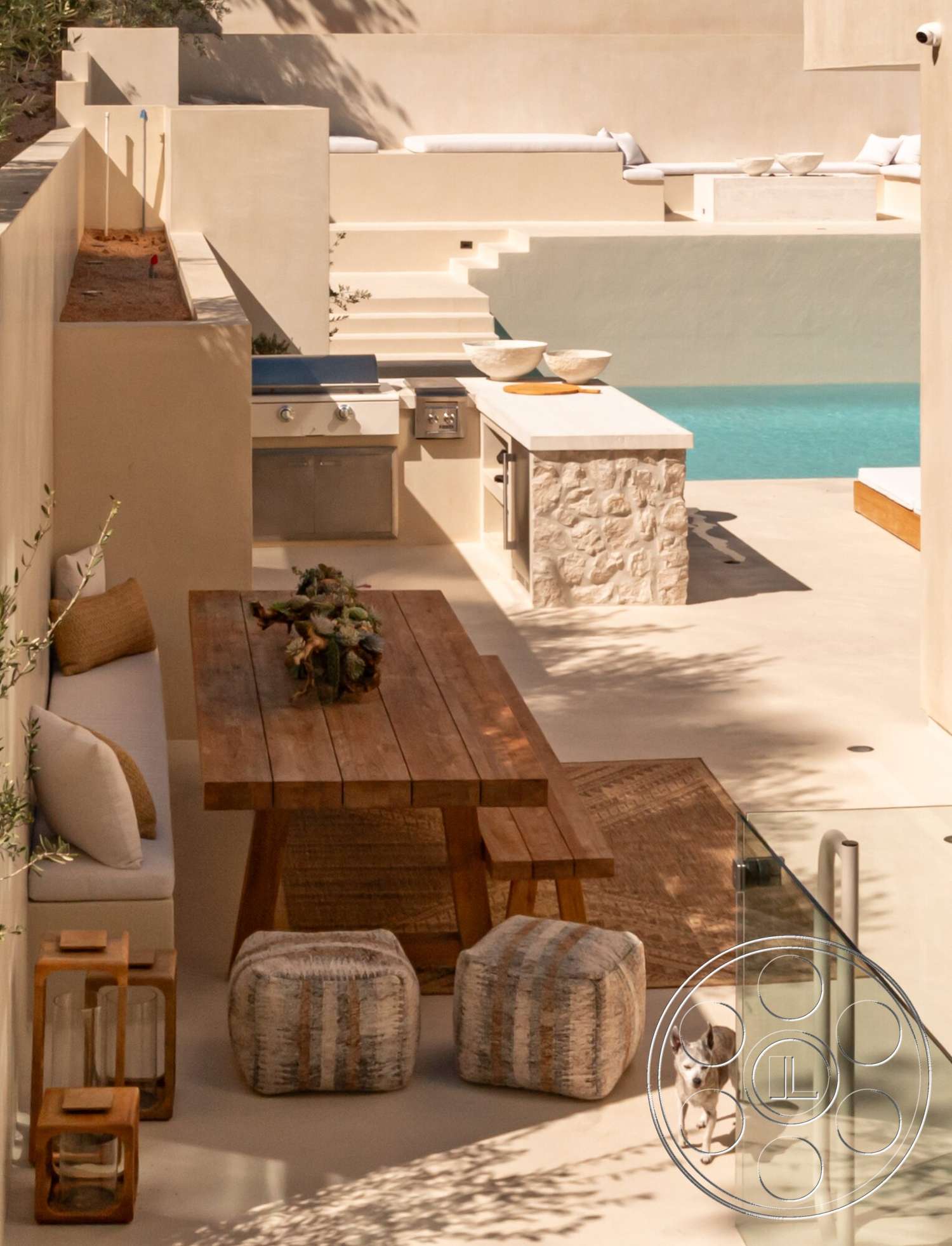 Modern 535 - exterior, wood dining table, woven area rug, rectangular pool, upholstered outdoor seating, plaster wall finish, modern outdoor living area, stainless steel outdoor grill, natural wood accent details, landscaped outdoor space, glass patio railing, stone outdoor kitchen countertop, sunny patio setting, concrete pool area, poufs with woven fabric