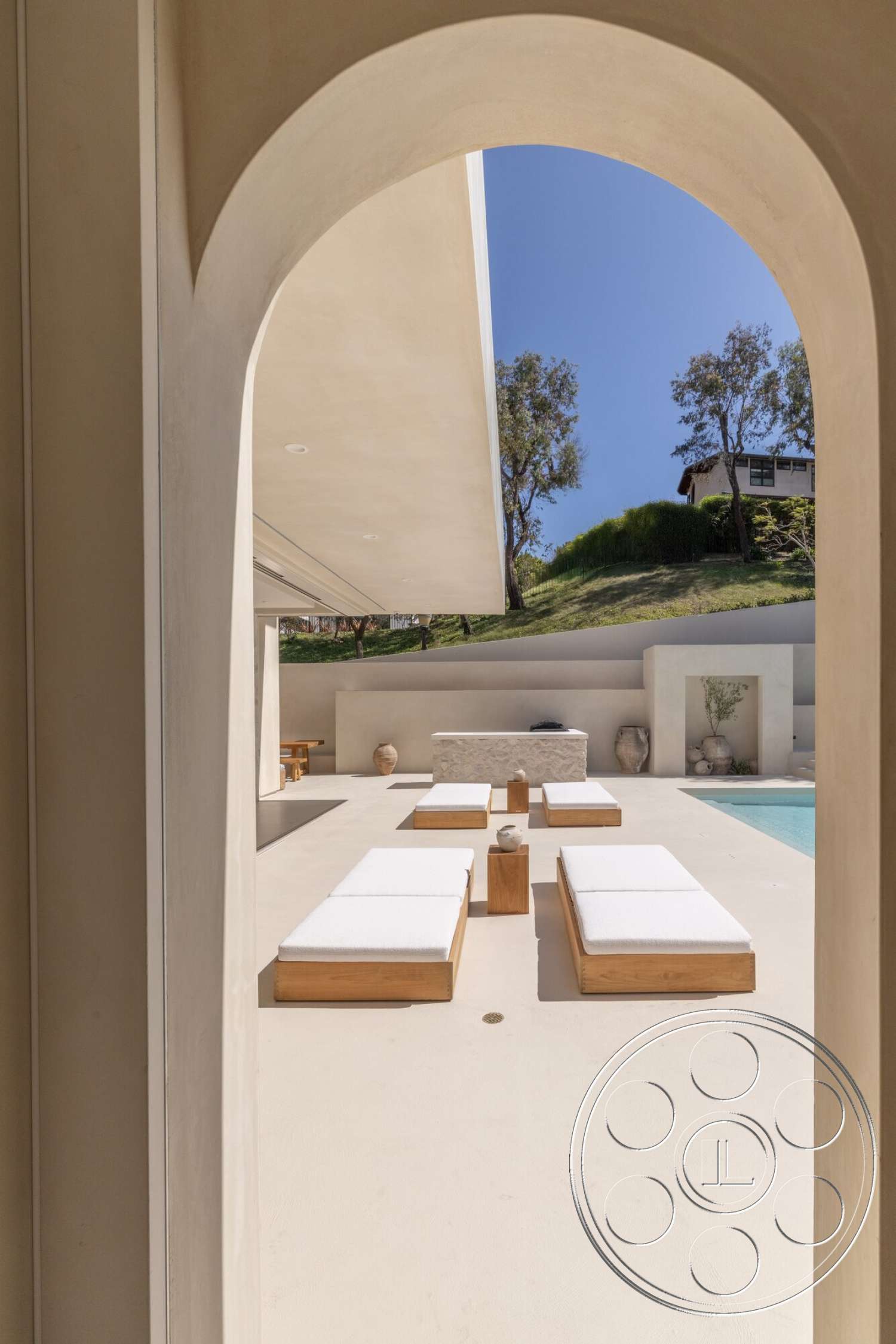 Modern 535 - exterior, rectangular swimming pool, outdoor lounge area, landscaped hillside, stucco walls, arched doorway, concrete patio floor, natural stone feature wall, wooden sun loungers