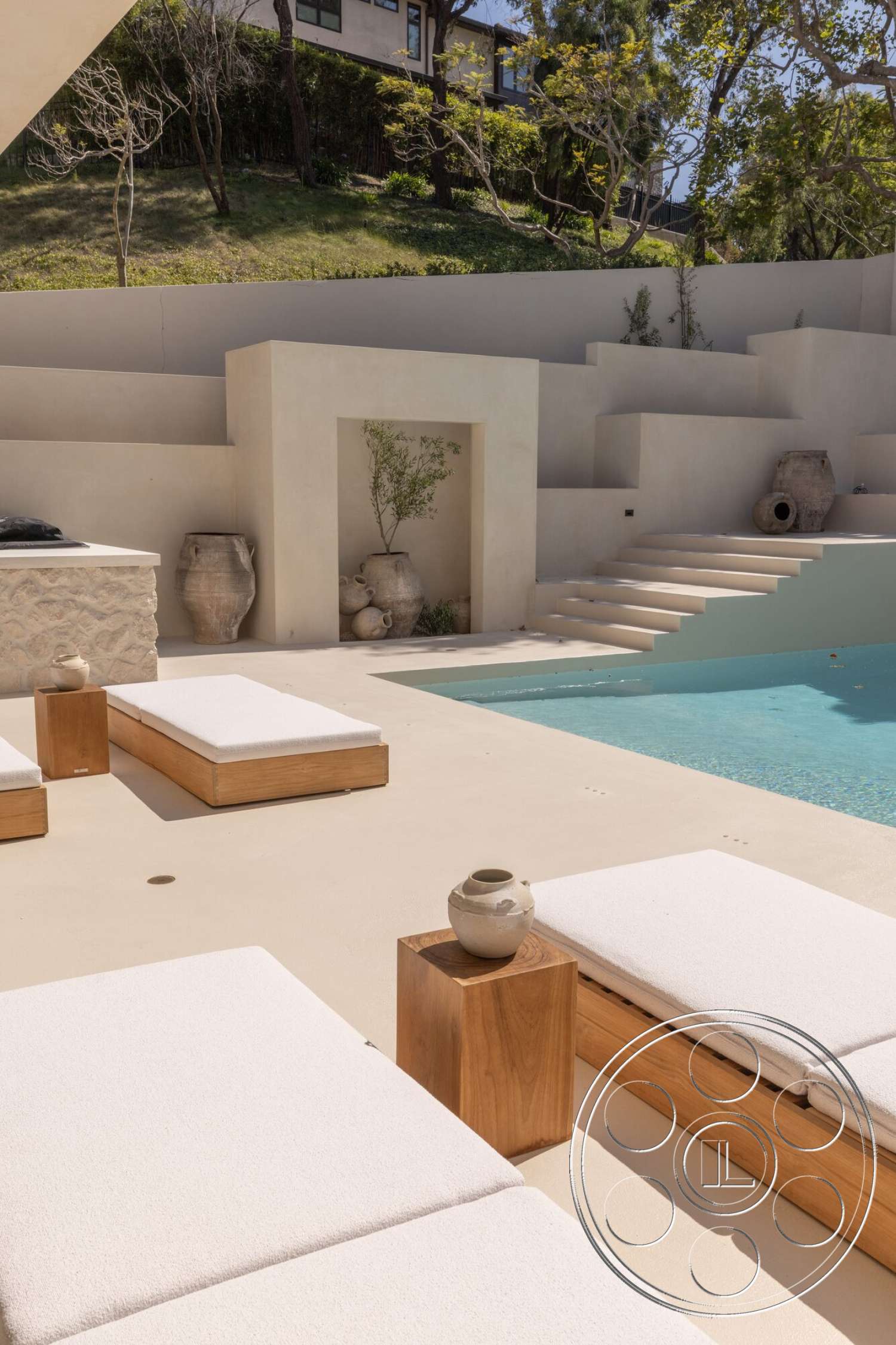 Modern 535 - exterior, wooden side tables, textured plaster walls, concrete pool deck, concrete patio flooring, custom wooden sun loungers, pool with rectangular shape, landscaped greenery background, ceramic vase on side table, staircase leading into pool area