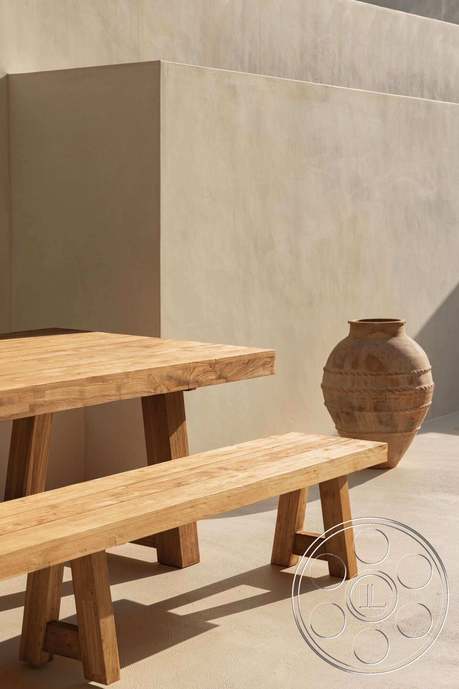 Modern 535 - exterior, wooden dining table, warm color palette, natural wood finishes, wooden bench seating, textured plaster wall, minimalist outdoor setting, plastered exterior wall, terra cotta pottery