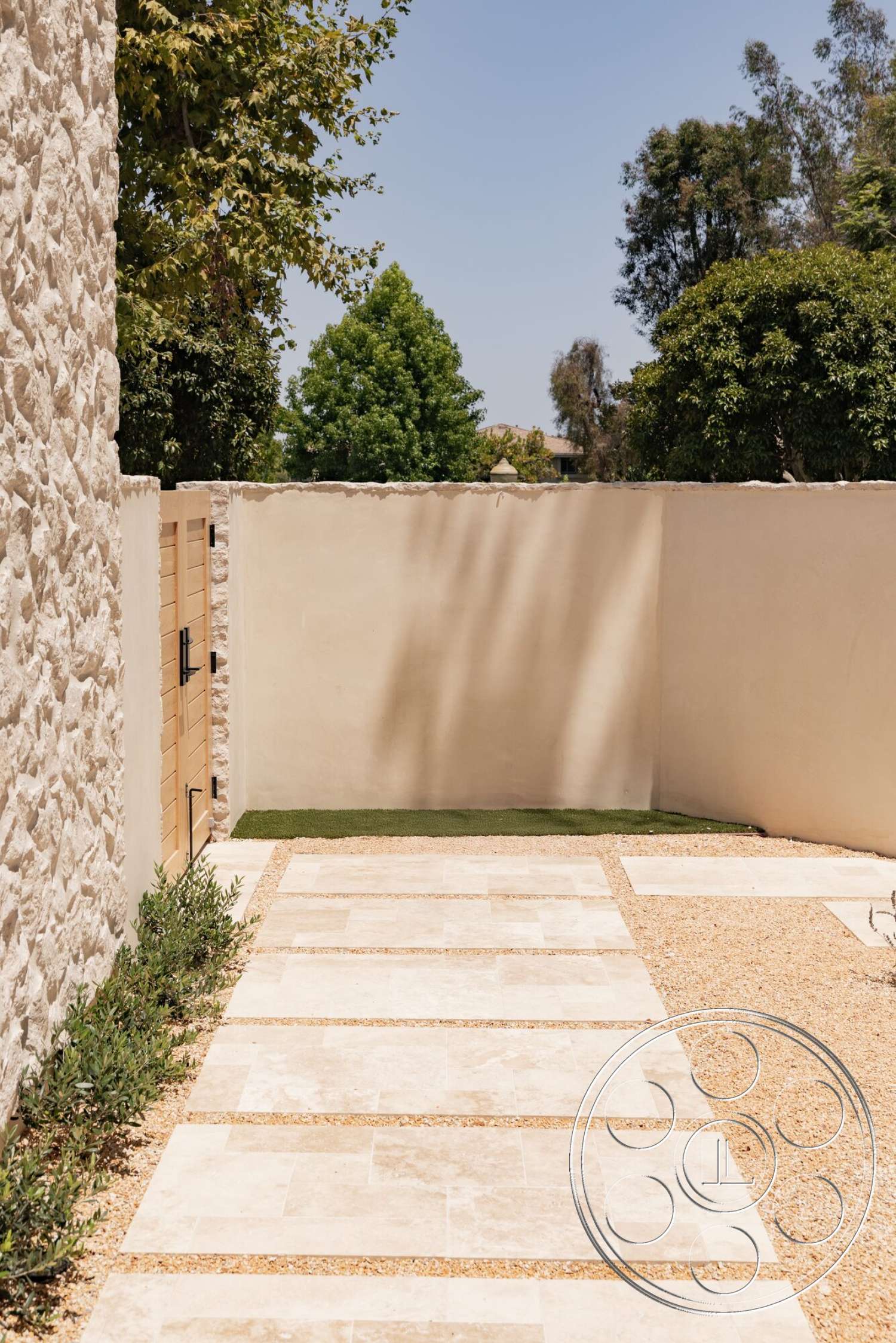 Modern 535 - exterior, landscaped greenery, concrete pathway, lawn area, flat stone pavers, wooden gate, horizontal wood fence, stone wall cladding, smooth plaster wall, gravel garden area, lush tree foliage