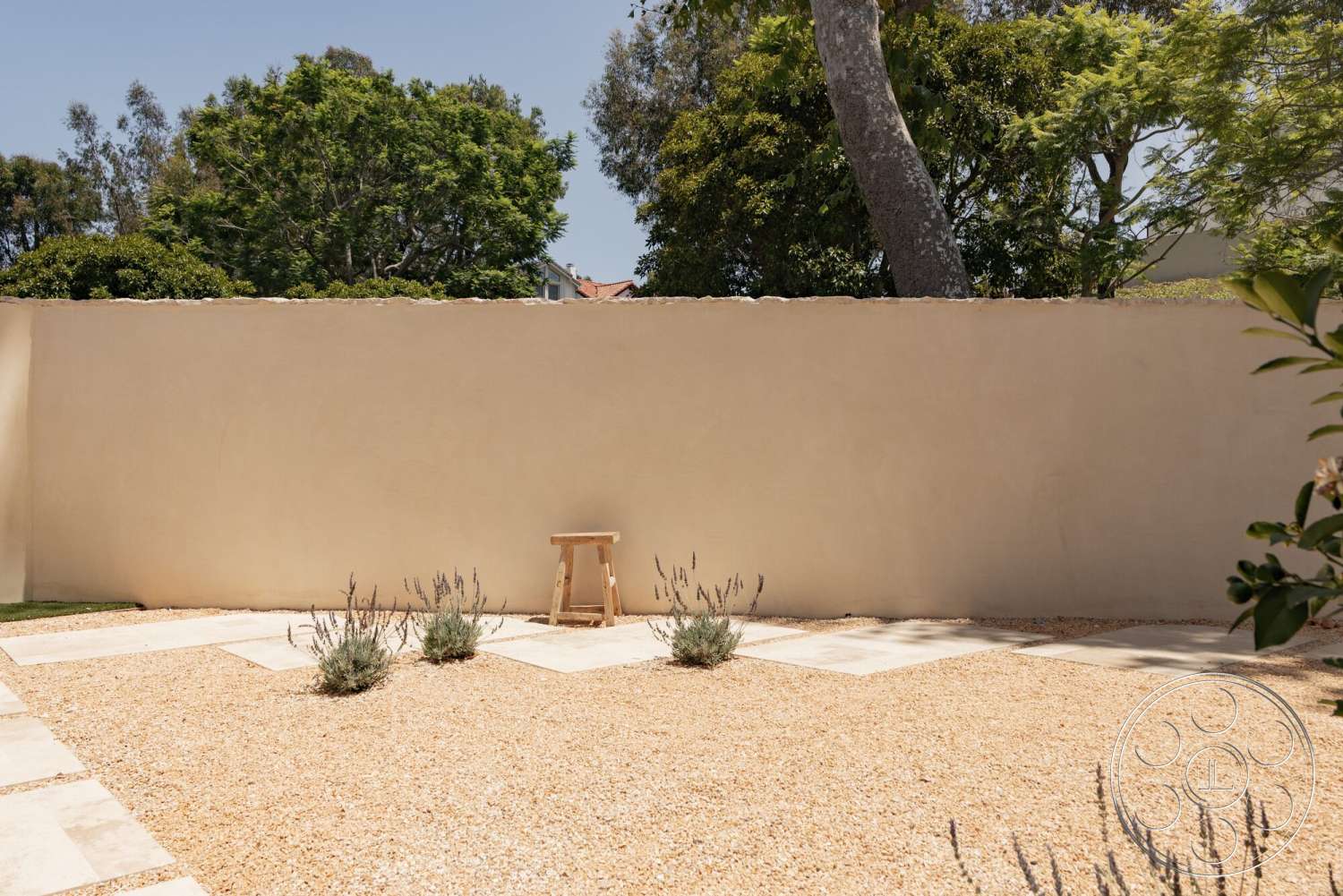 Modern 535 - exterior, wooden stool, stucco wall, smooth wall finish, rectangular patio layout, tropical foliage backdrop, concrete patio pavers, gravel landscape area, lavender plant beds