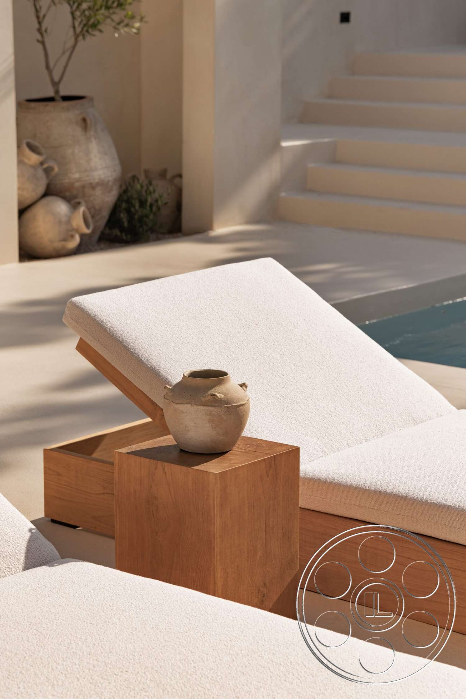Modern 535 - exterior, plaster wall finish, concrete patio flooring, minimalist outdoor design, natural wood side table, soft sunlight illumination, wood sun lounger frame, upholstered sun lounger cushions, stone decorative pot, gentle staircase leading to pool, lush greenery accent, calm poolside environment
