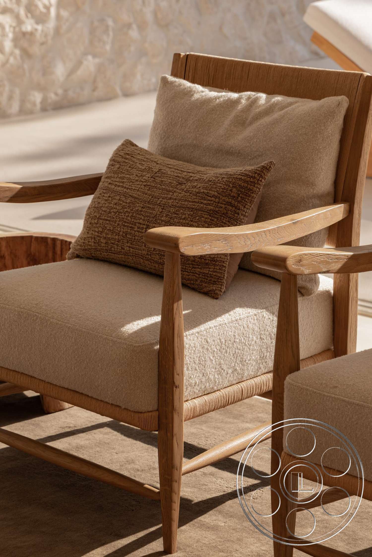 Modern 535 - natural light-filled space, wooden lounge chair with natural finish, beige upholstered seat cushion, textured throw pillow in warm tones, soft fabric cushion, woven seat detailing, light-toned wood armrests, neutral-colored area rug, exposed stone wall backdrop
