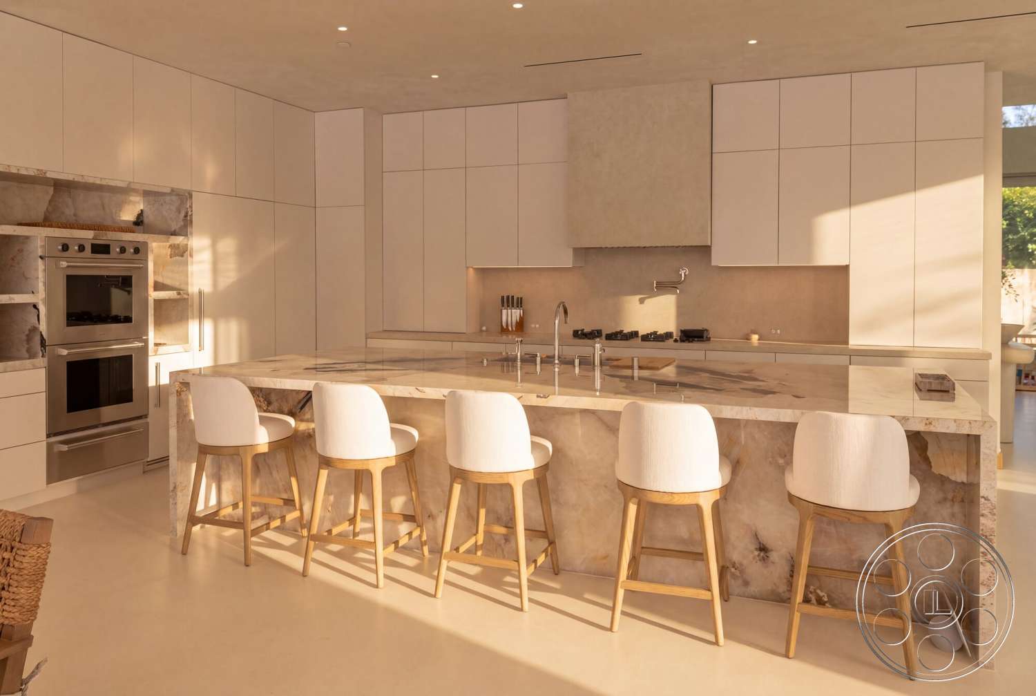Modern 535 - open layout, stainless steel appliances, white cabinetry, soft natural lighting, modern bar stools, marble kitchen island countertop, minimalist kitchen design, sparse wall decor, backlit wall panels, light-colored laminate flooring, streamlined kitchen faucet