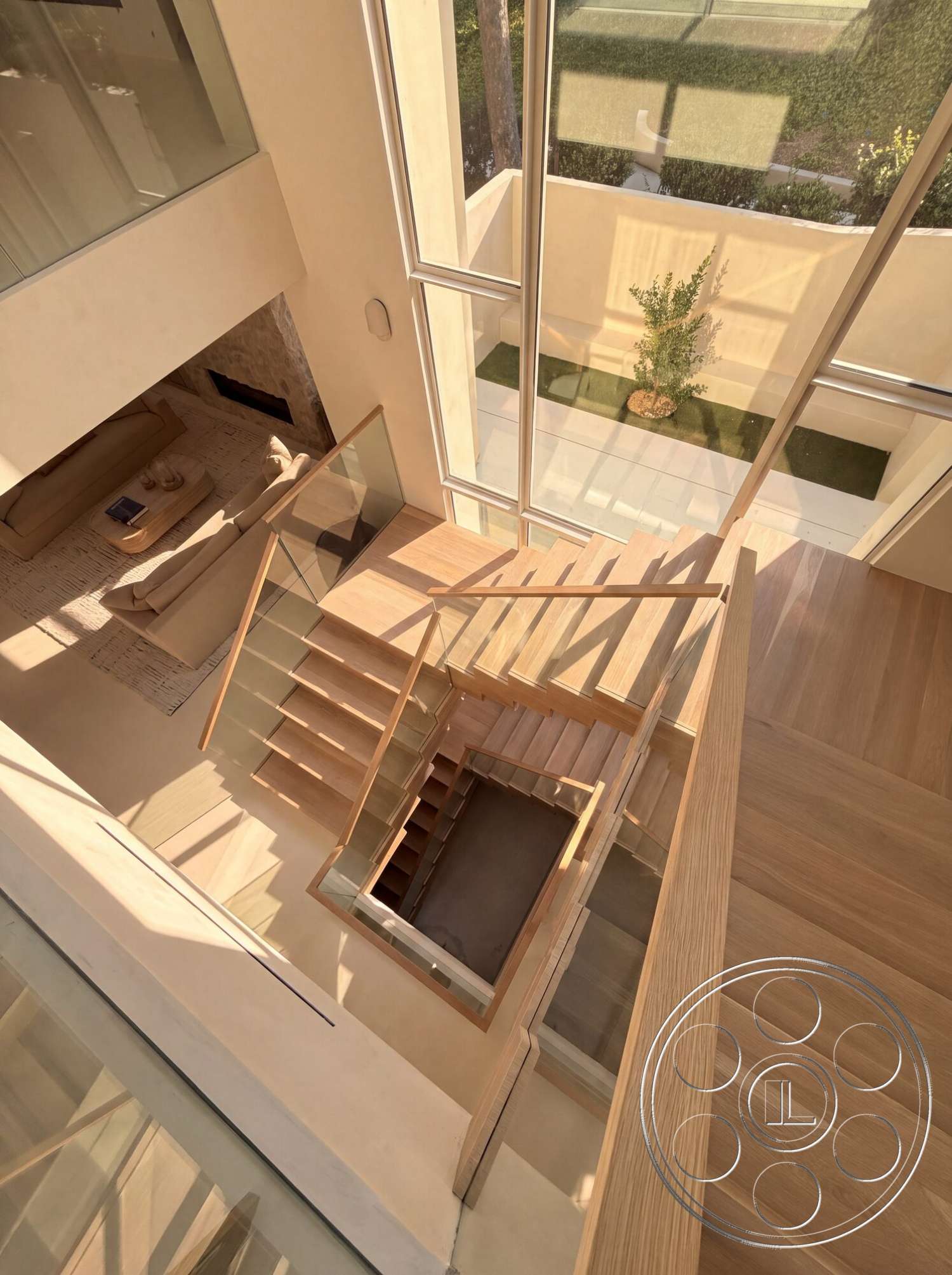 Modern 535 - hardwood flooring, glass railing, modern architectural style, natural light through large windows, open atrium space, light-colored plaster walls, wooden floating staircase, view of landscaped courtyard