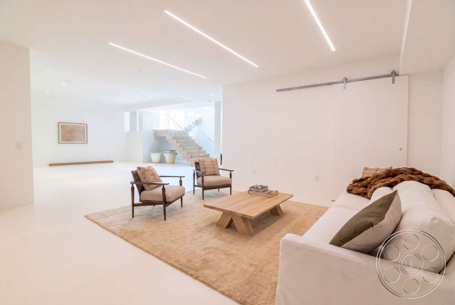 Modern 535 - neutral color palette, large open space, floor-to-ceiling windows, smooth concrete flooring, contemporary aesthetic, plush area rug, recessed ceiling lighting, white painted walls, modern armchairs, minimalist wooden coffee table, straight staircase with glass railing, sliding barn door hardware