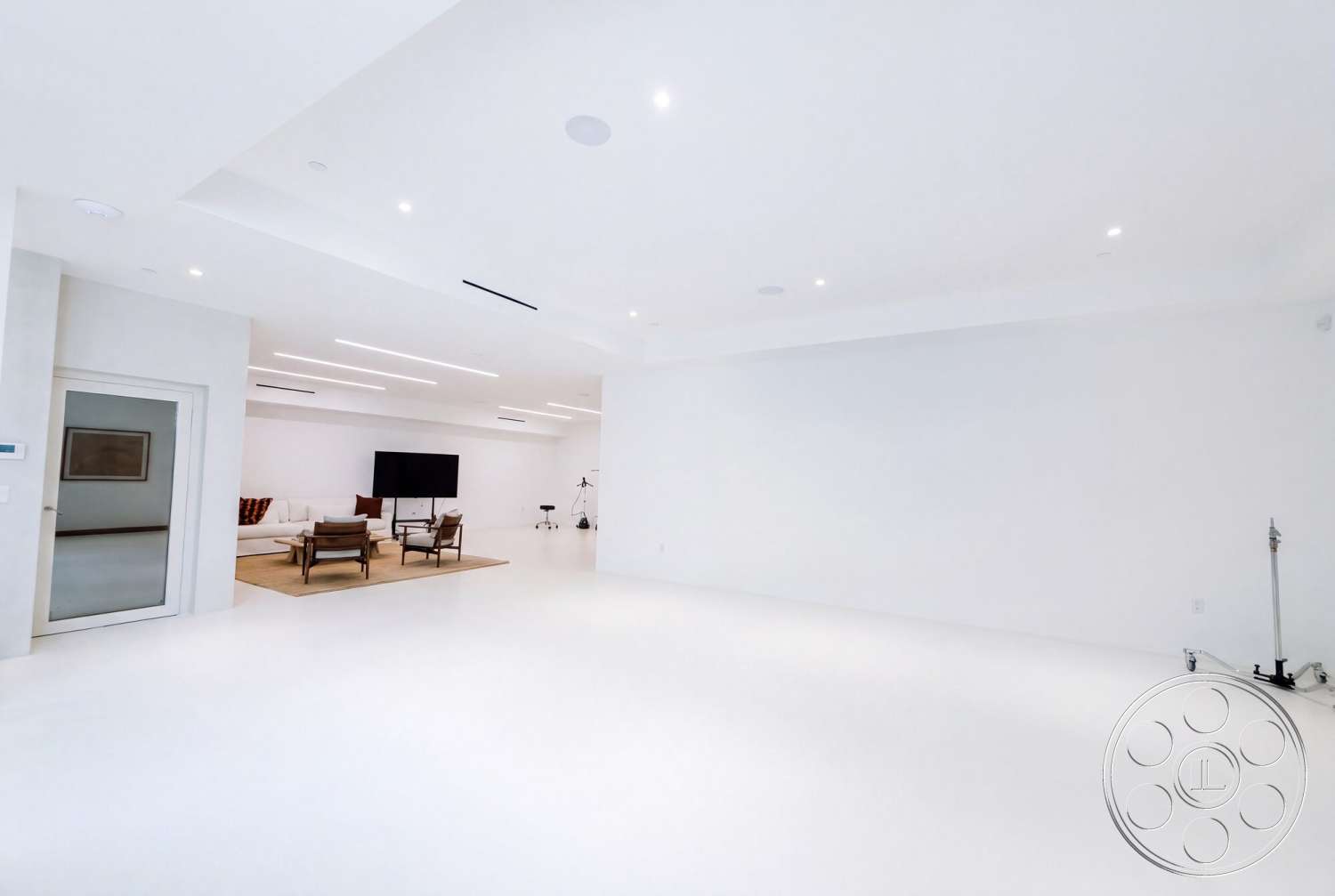 Modern 535 - minimalist furniture, decorative wall art, textured plaster walls, modern lounge area, acoustic ceiling panels, natural fiber area rug, drop ceiling with recessed lighting, flat-screen television wall, white seamless floor, glass door on entry