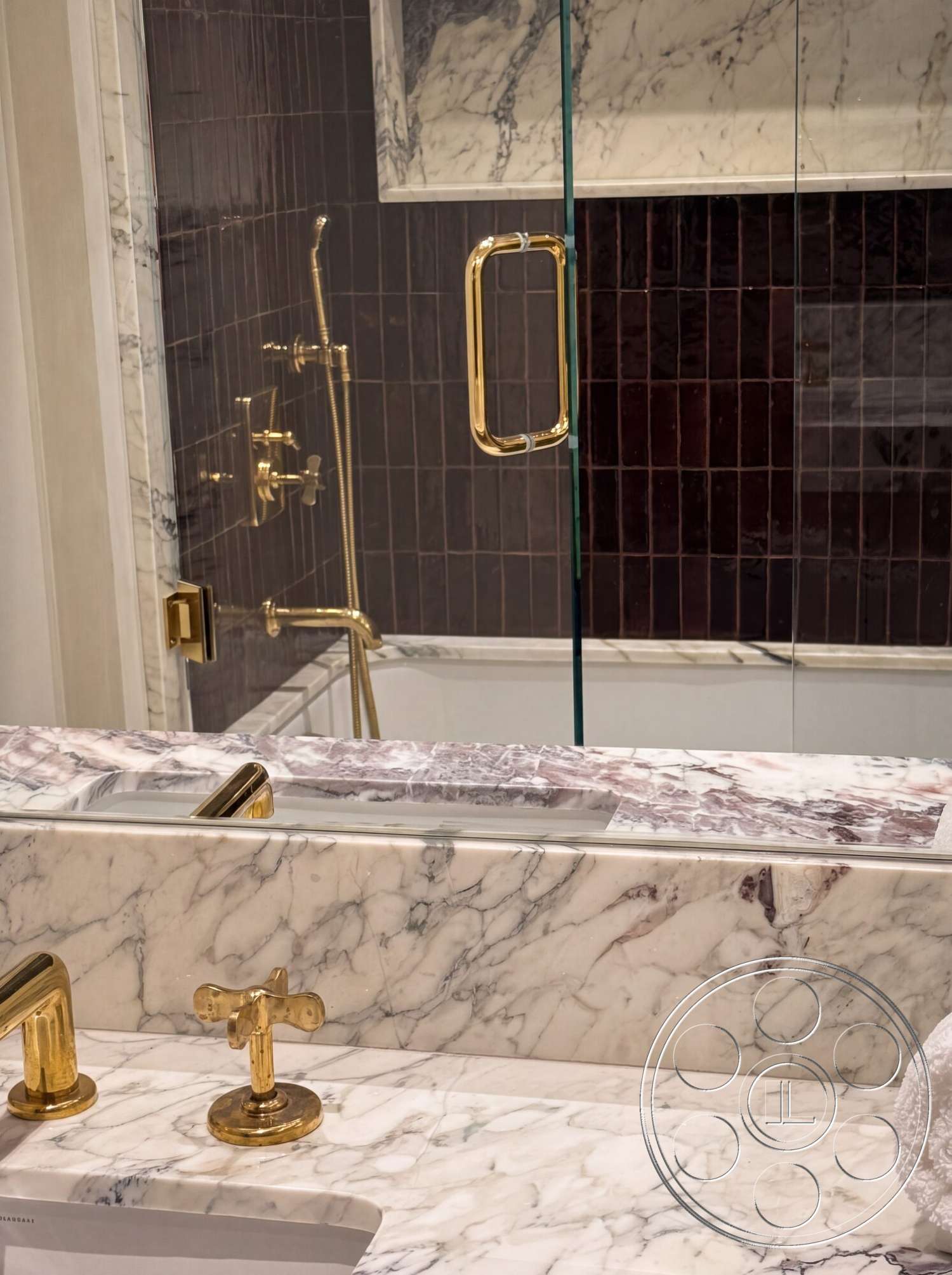 Modern 535 - modern design, glass shower enclosure, marble countertop, luxury bathroom, gold faucet fixtures, gold shower controls, marble sink area, dark tiled shower walls, exposed marble backsplash