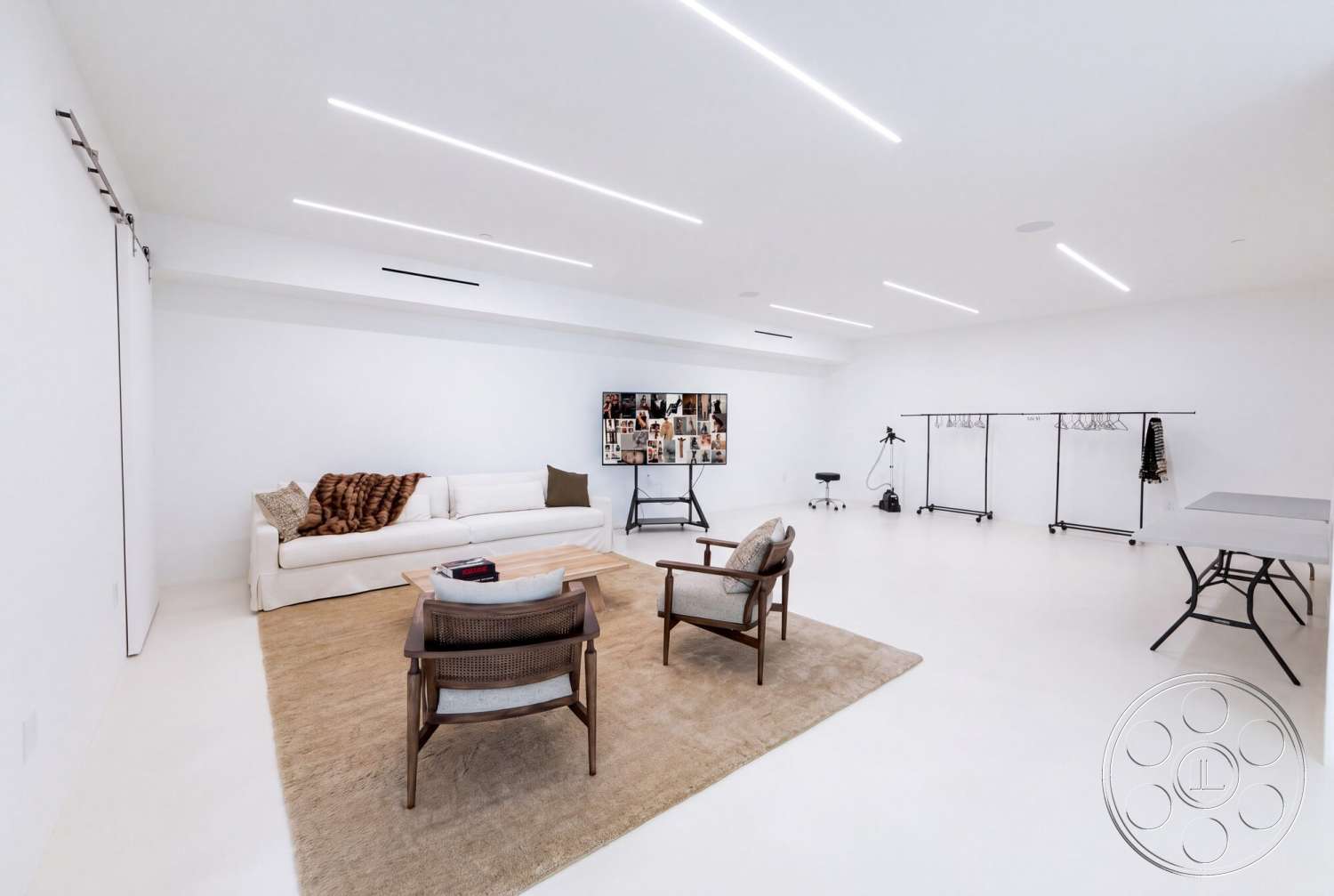 Modern 535 - open layout, creative workspace, sectional sofa, smooth concrete flooring, soft area rug, rectangular coffee table, folding table, clothing racks, modern minimalist design, white painted walls, track lighting fixtures, wood accent chairs