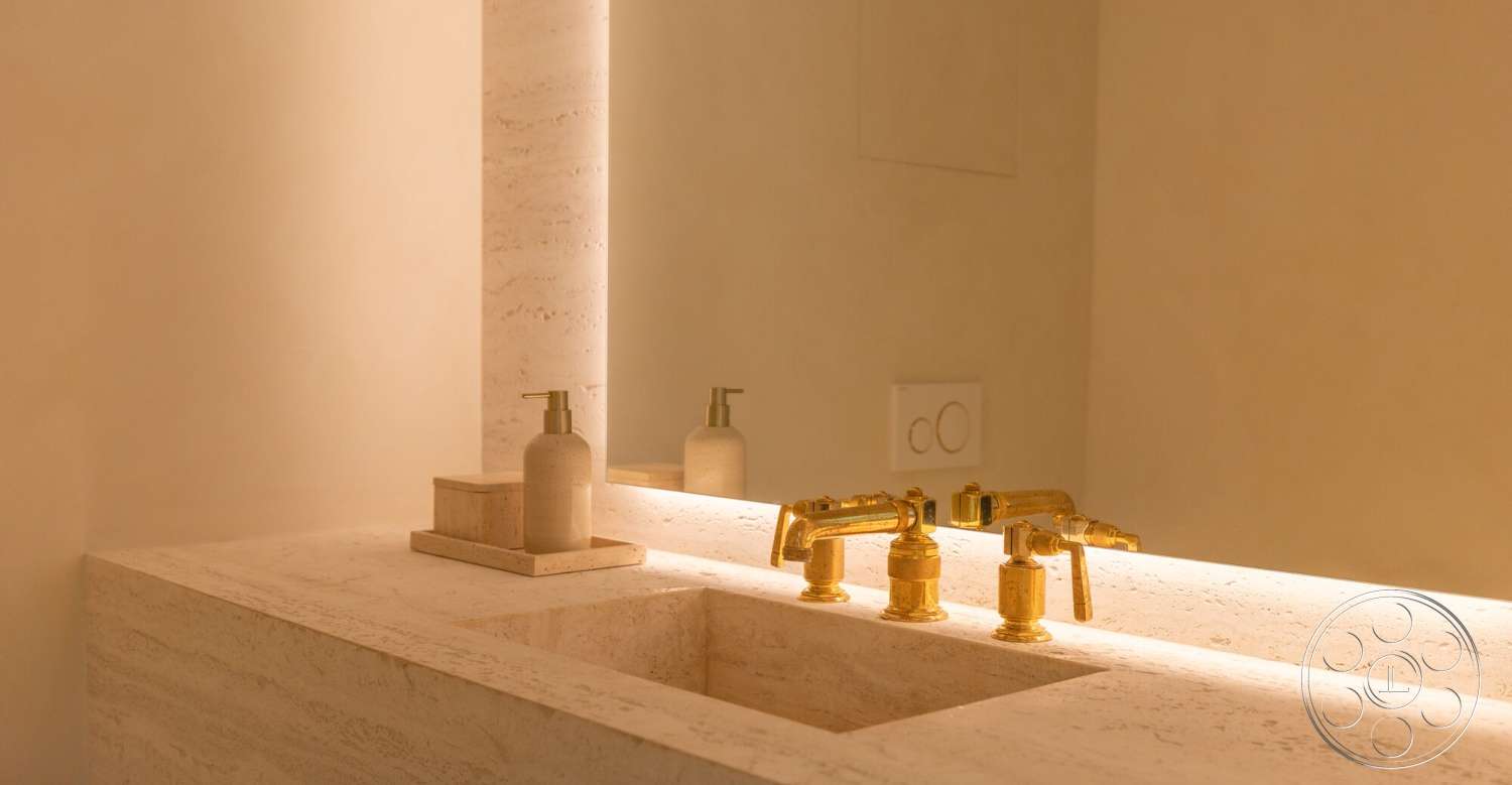 Modern 535 - neutral color palette, soft ambient lighting, textured plaster walls, stone feature wall, under-mounted sink, minimalist bathroom design, brass faucet fixtures, geometric mirror design, travertine bathroom countertop