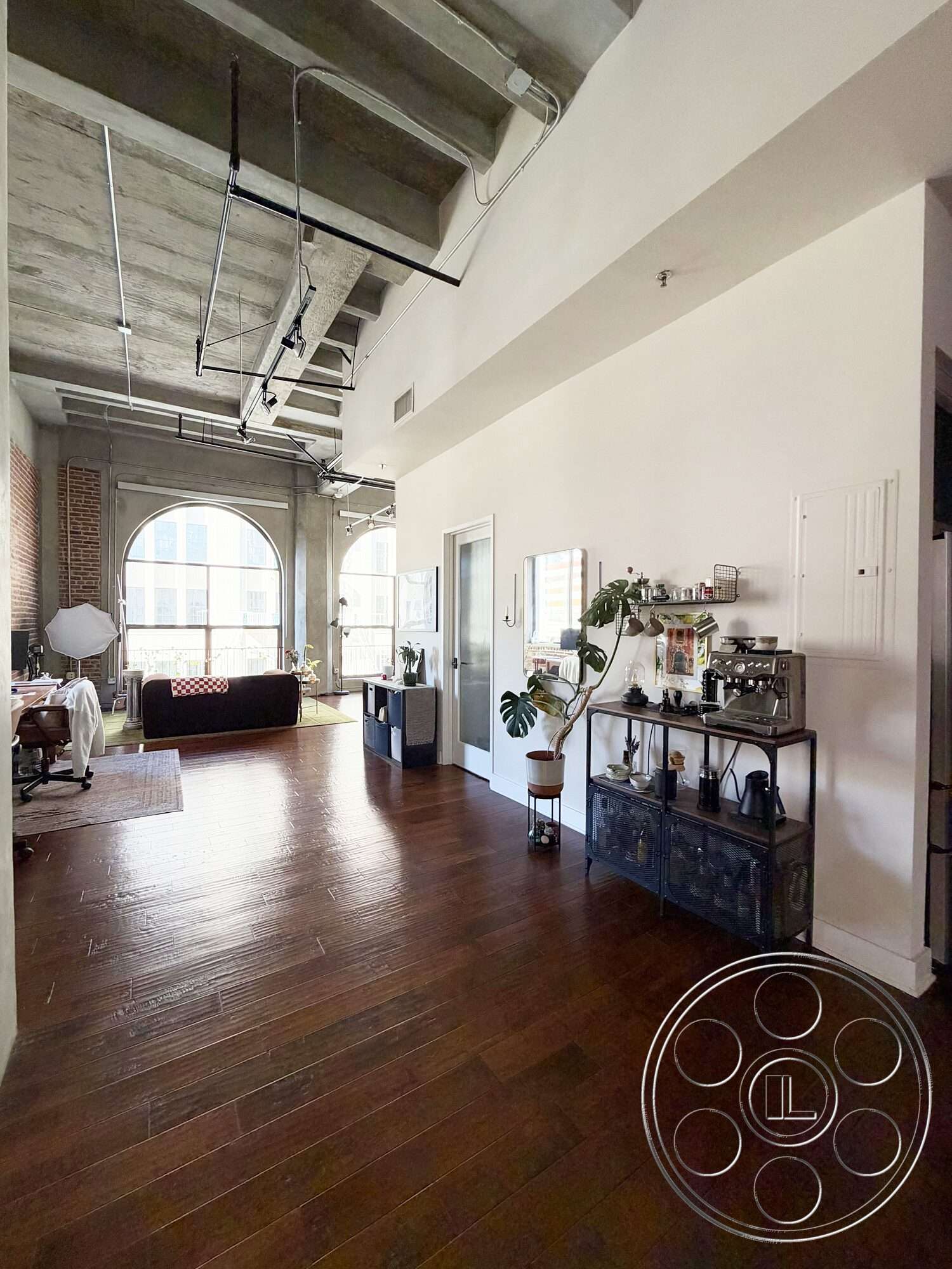 Brockman 310 - natural lighting, open floor plan, metal shelving unit, dark hardwood flooring, exposed concrete ceiling, arched windows, exposed brick accent wall, industrial-style interior, urban loft setting, modern home office area