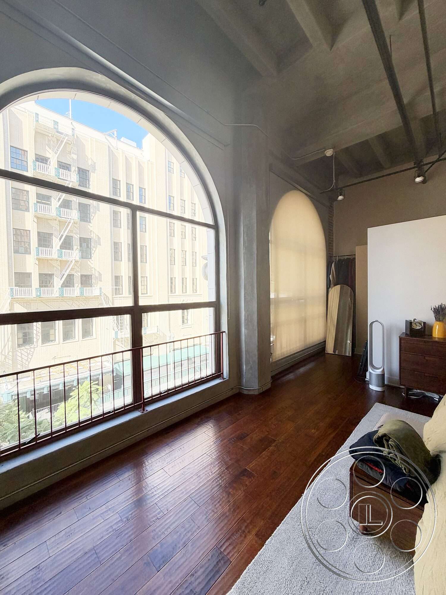 Brockman 310 - minimalist decor, natural light, hardwood flooring, wooden furniture, metal railing, soft area rug, open living space, modern urban setting, exposed concrete ceilings, arched large windows