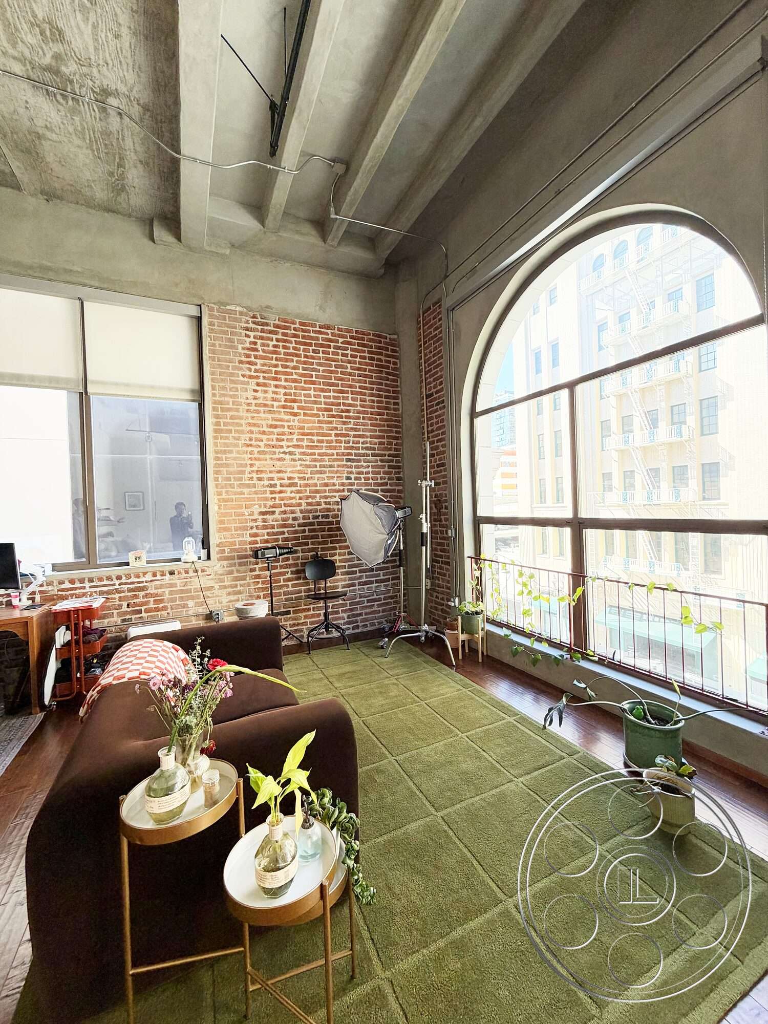 Brockman 310 - natural light, hardwood flooring, potted plants, area rug, studio space, concrete ceiling, arched windows, exposed brick accent wall, urban loft setting, modern accent tables, contemporary seating
