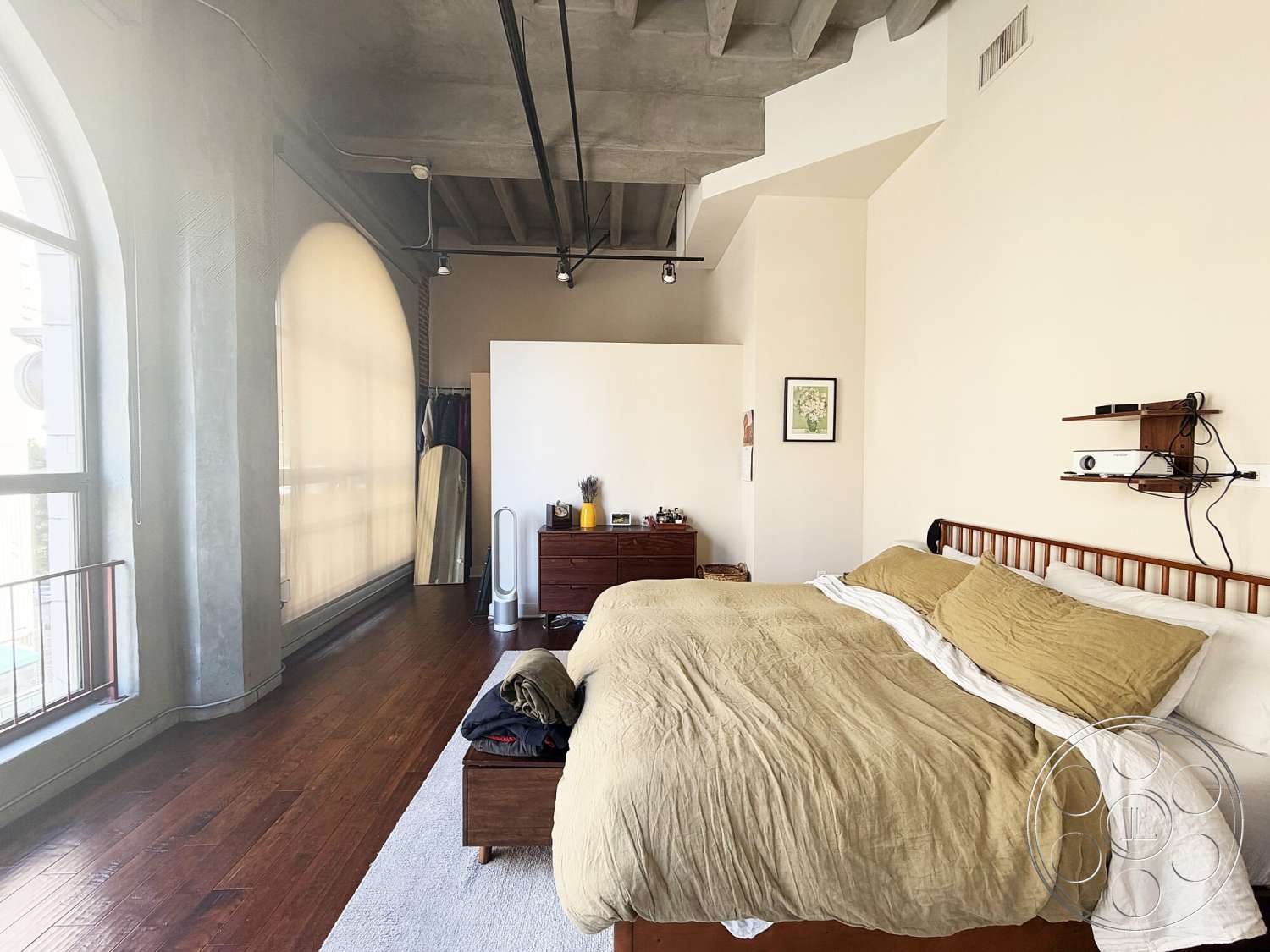 Brockman 310 - natural light, floor-to-ceiling windows, exposed concrete ceiling, minimalist interior design, hardwood bedroom floors, neutral painted walls, curved window shapes, urban loft setting, decorative wall shelf, modern wooden bed frame, casual bedding