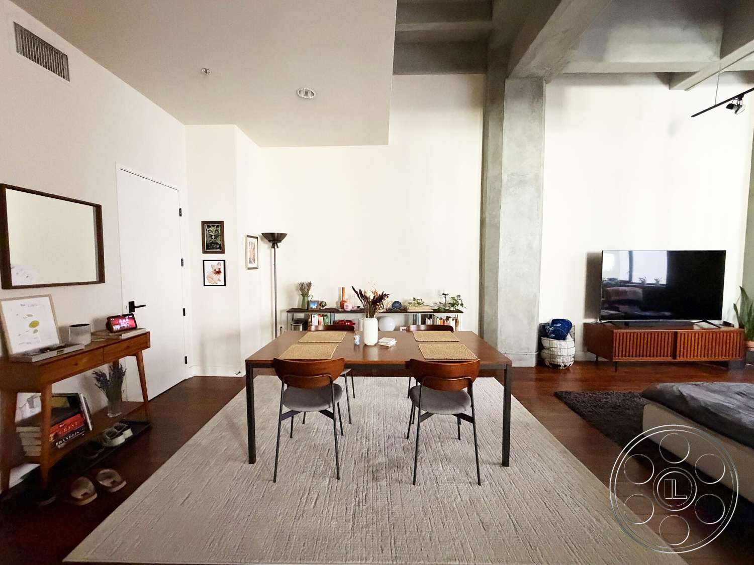 Brockman 310 - open floor plan, area rug, sectional sofa, floor lamp, decorative wall art, rectangular dining table, large flat-screen television, hardwood living room floors, modern minimalist design, concrete ceiling beams, glass and wood coffee table, light-colored textured walls, fabric dining chairs, wood media console