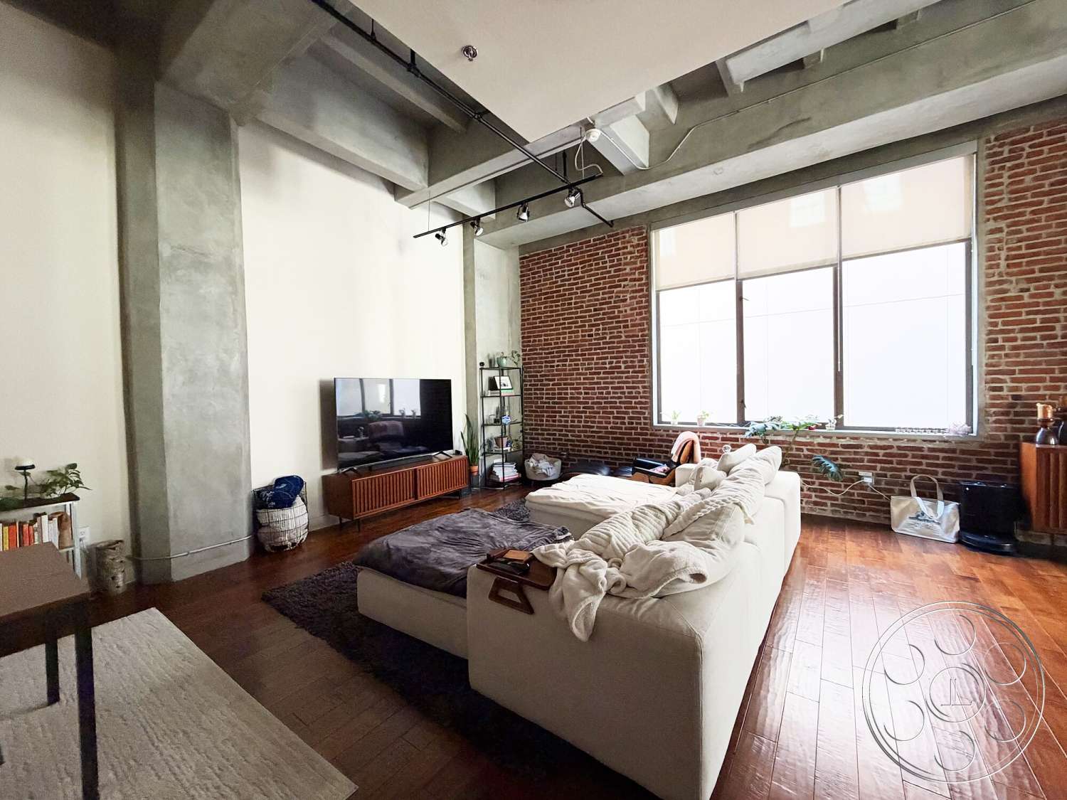 Brockman 310 - minimalist decor, large windows, open floor plan, textured plaster walls, modern entertainment unit, concrete ceiling, steel railings, hardwood living room floors, exposed brick accent wall, industrial style lighting, modern sofas