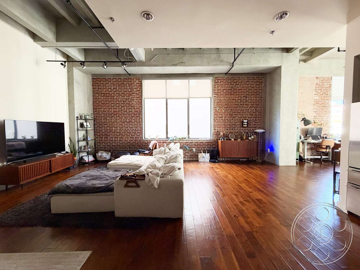 Brockman 310 - minimalist decor, neutral color palette, large windows, open floor plan, concrete ceiling, flat-screen television, contemporary coffee table, hardwood living room floors, modern sectional sofa, exposed brick accent wall, industrial shelving unit, cozy area rug, steel radiator