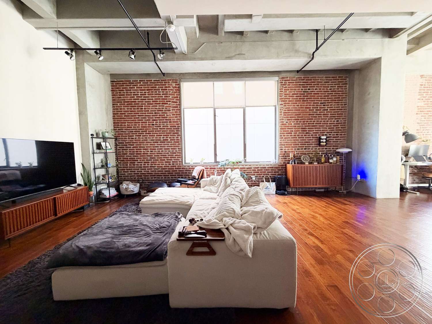 Brockman 310 - minimalist decor, neutral color palette, open floor plan, modern entertainment unit, concrete ceiling, contemporary seating area, hardwood living room floors, exposed brick accent wall, large windows with natural light, industrial-style lighting fixtures, urban loft setting