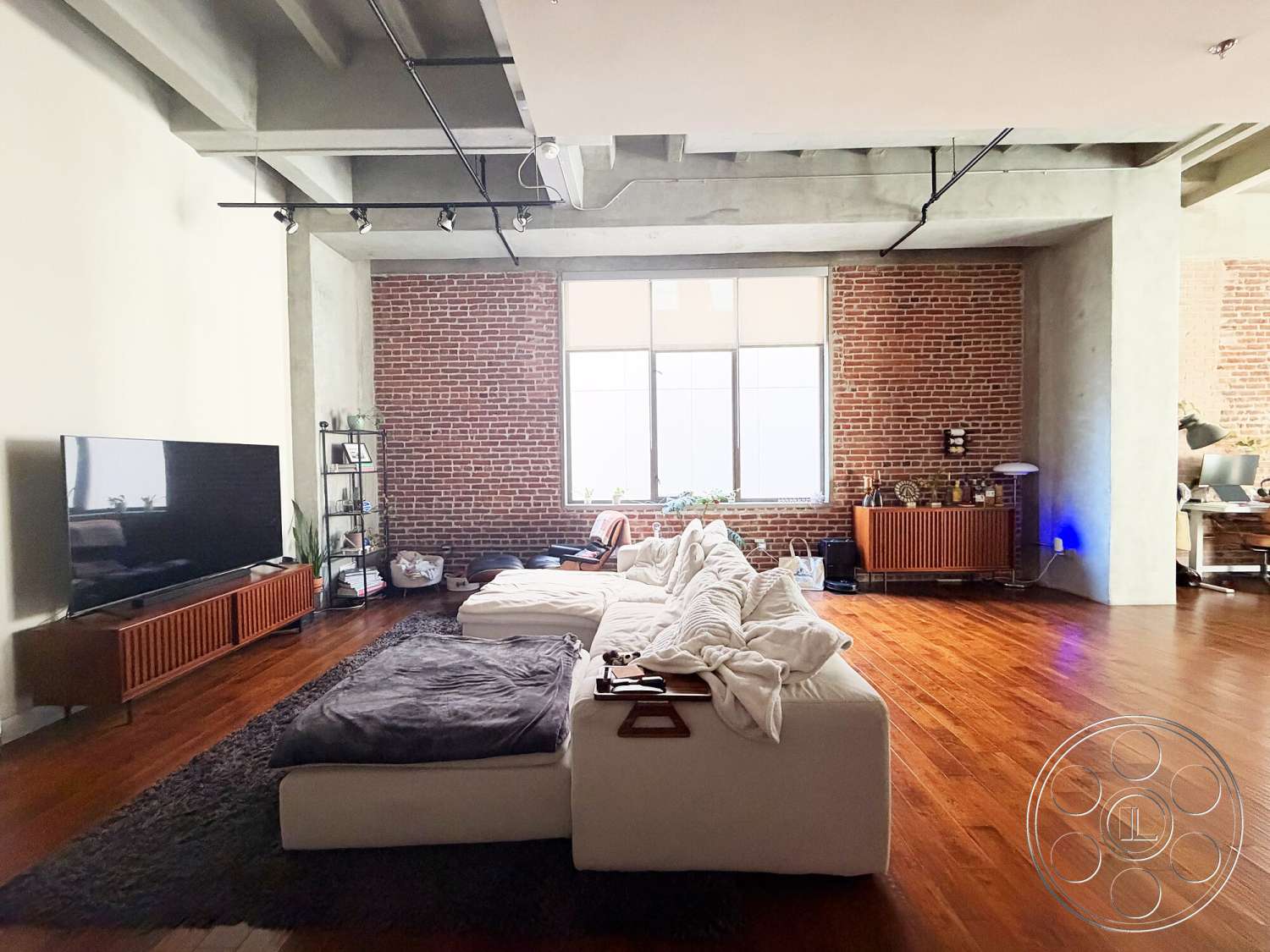 Brockman 310 - neutral color palette, open concept layout, concrete ceiling, hardwood living room floors, modern sectional sofa, exposed brick accent wall, industrial shelving unit, large floor-to-ceiling window, minimalist media console