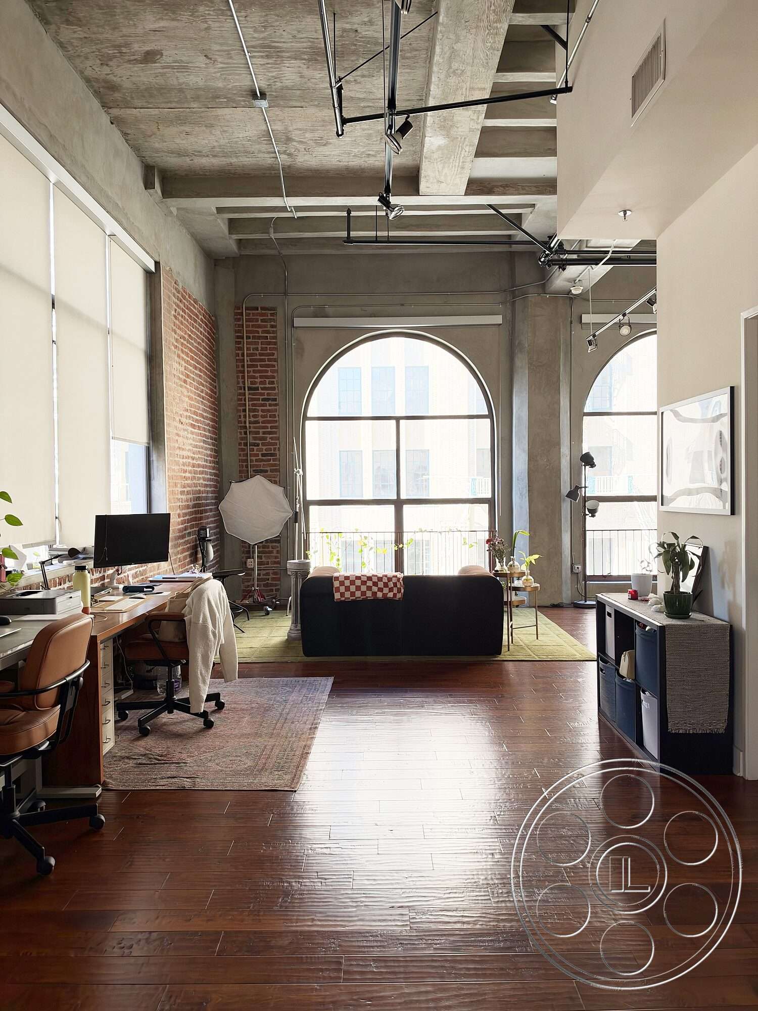 Brockman 310 - hardwood flooring, decorative area rug, open floor plan, minimalist furniture, modern workspace, concrete ceiling, large arched windows, contemporary interior, natural light illumination, exposed brick accent wall, urban loft setting, industrial ceiling beams, stylish living area