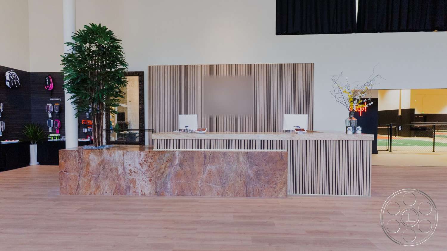 Gym 38 - minimalist decor, large open space, floor-to-ceiling windows, marble reception desk, wood laminate flooring, modern reception area, tall indoor plants, striped wood wall